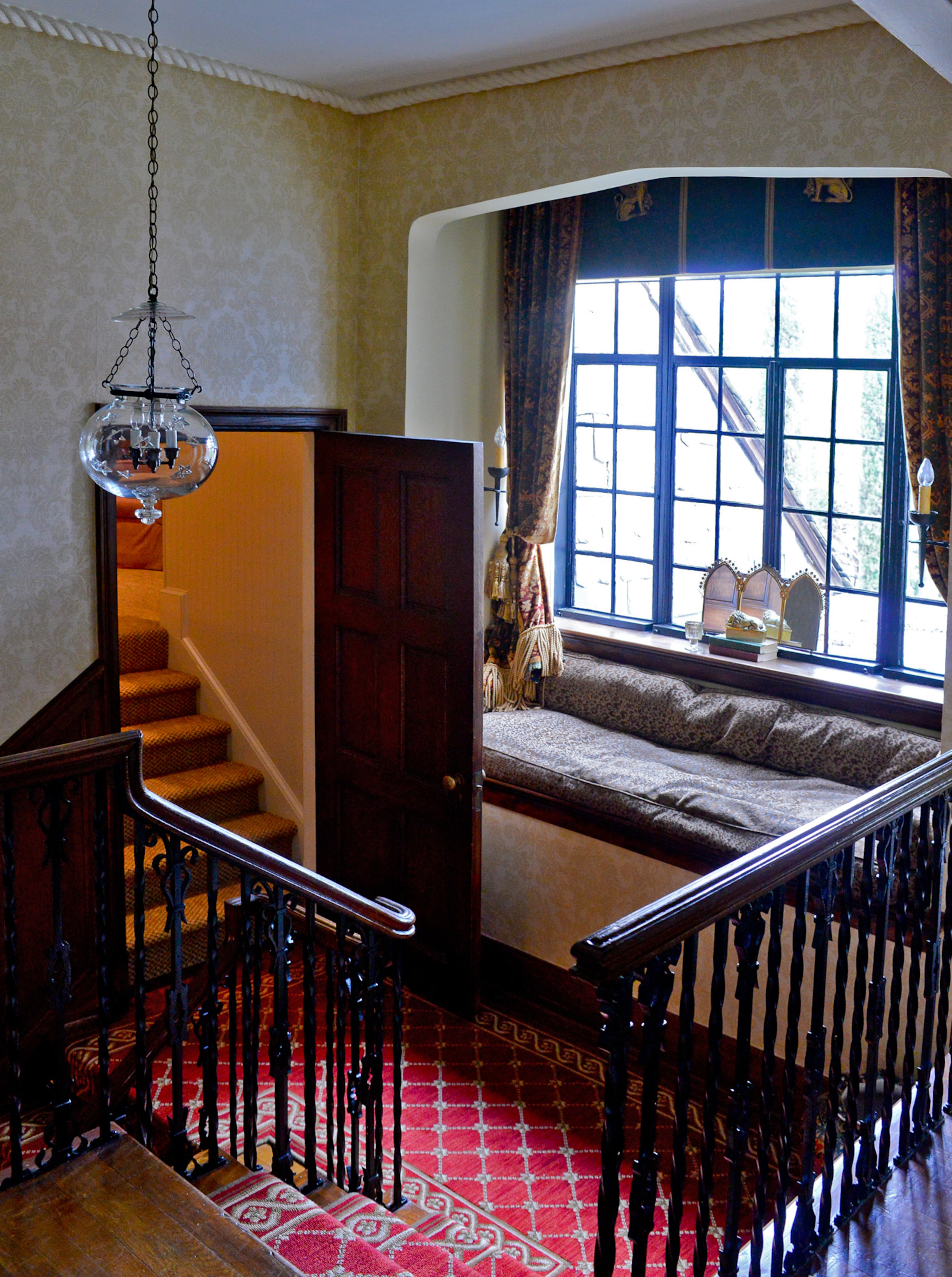 A window seat on the stair landing, surrounded by antique French iron sconces from Boxwoods Gardens & Gifts, offers the family a comfortable spot to look outside or reflect upon the restored beauty of the home's interior.
