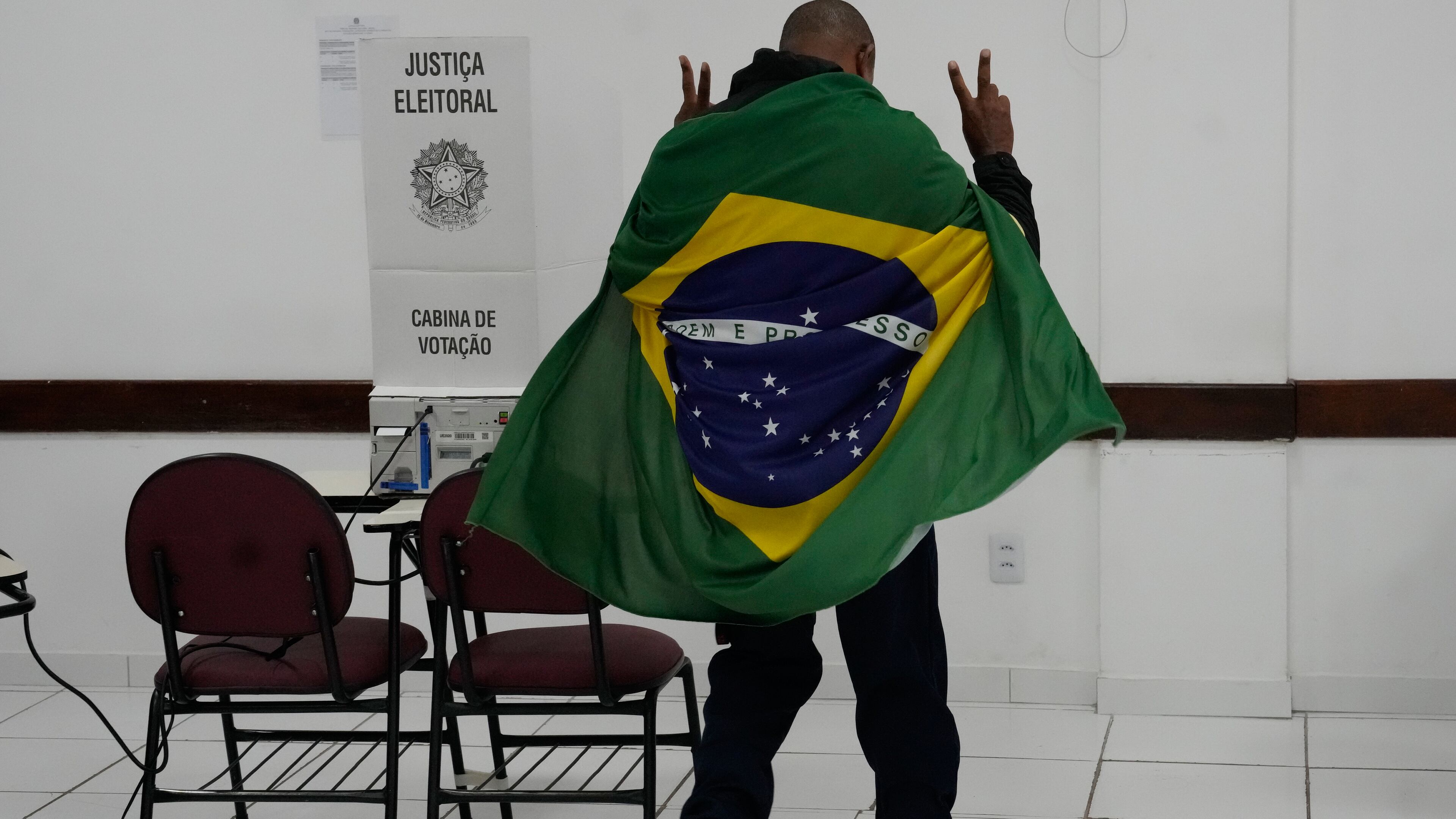 A man wrapped in a Brazilian flag arrives to vote in the presidential runoff in Brasilia, Brazil, Sunday, Oct. 25, 2026. (AP Photo/Eraldo Peres)