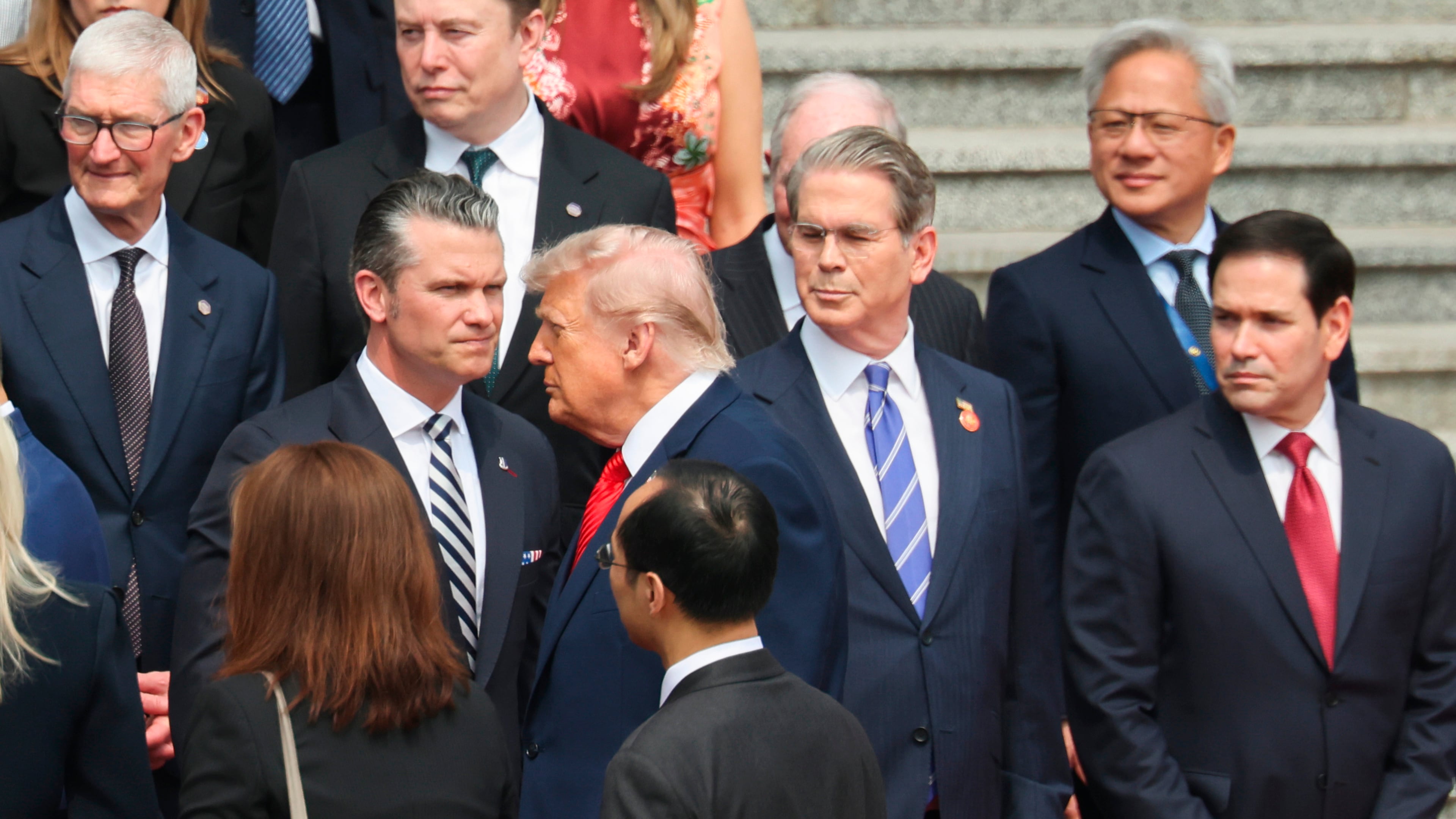 U.S. President Donald Trump looks on next to, from bottom right, U.S. Secretary of State Marco Rubio, U.S. Treasury Secretary Scott Bessent, U.S. Defense Secretary Pete Hegseth, Nvidia CEO Jensen Huang, top right, Tesla CEO Elon Musk, Apple CEO Tim Cook, top left, and others during a welcome ceremony at the Great Hall of the People in Beijing, Thursday, May 14, 2026. (Maxim Shemetov/Pool Photo via AP)