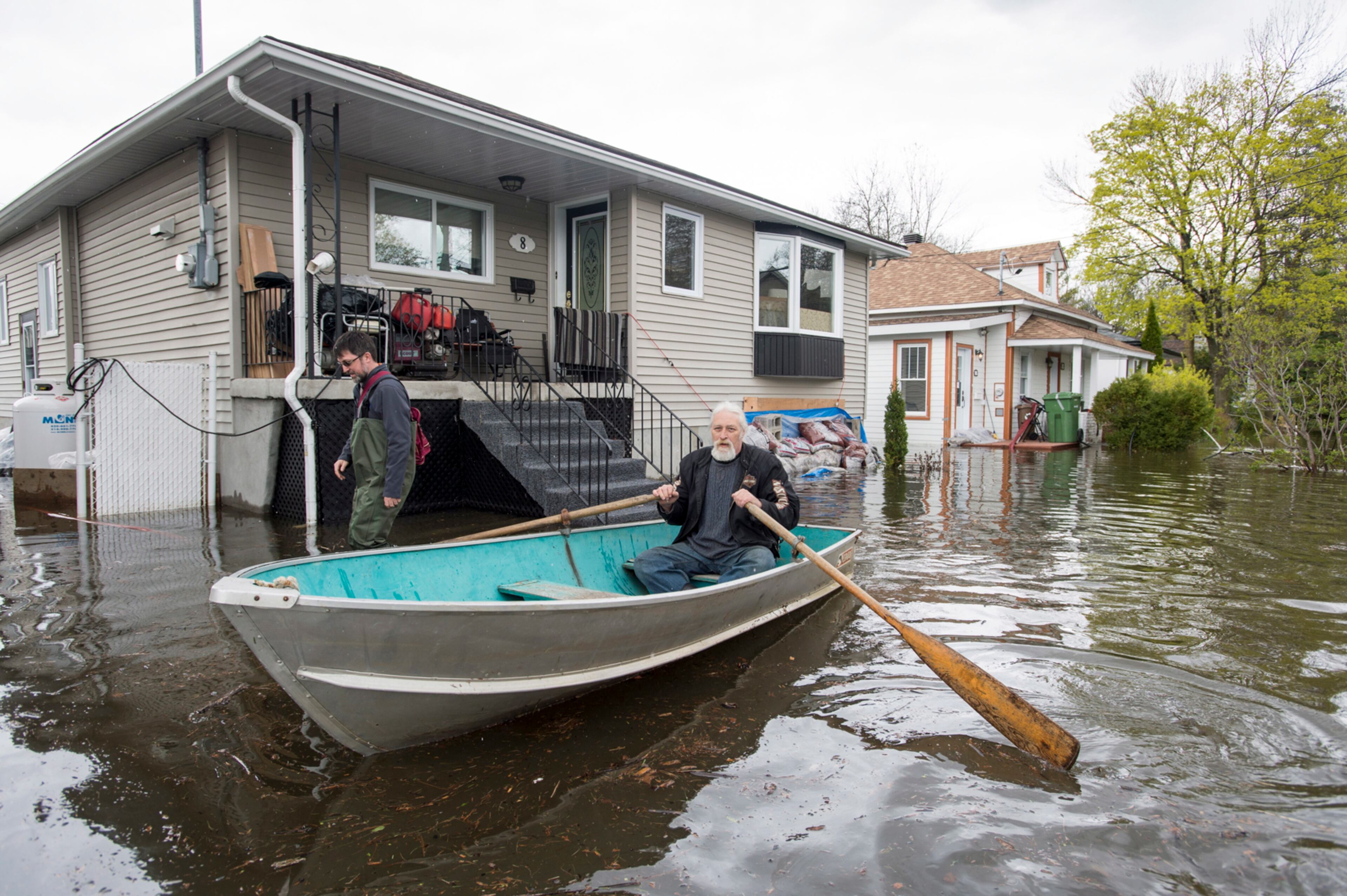 A man rows his boat down a street in the Cartierville district of Montreal on Tuesday, May 9, 2017. More than 1,500 soldiers hit the ground Monday to help Quebecers deal with "historic" flooding that has caused widespread damage and evacuations. (Paul Chiasson/The Canadian Press via AP)