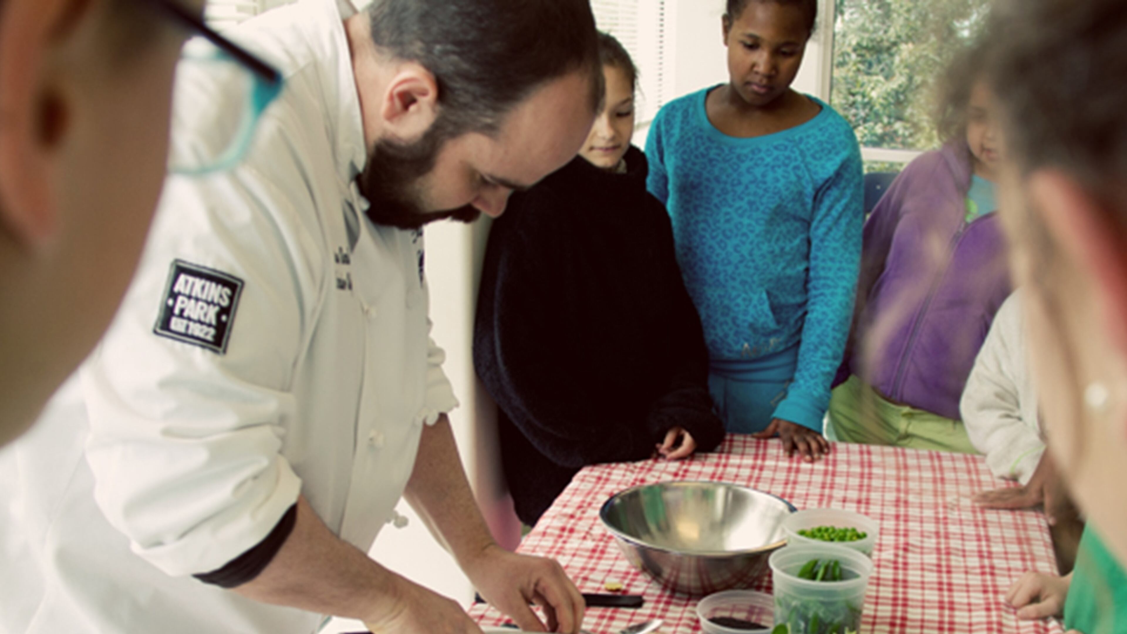 Chef Andrew Smith of Atkins Park restaurant shows students from Springdale Park elementary how to prepare produce raised in the school's gardens. Credit:Jenna Mobley.