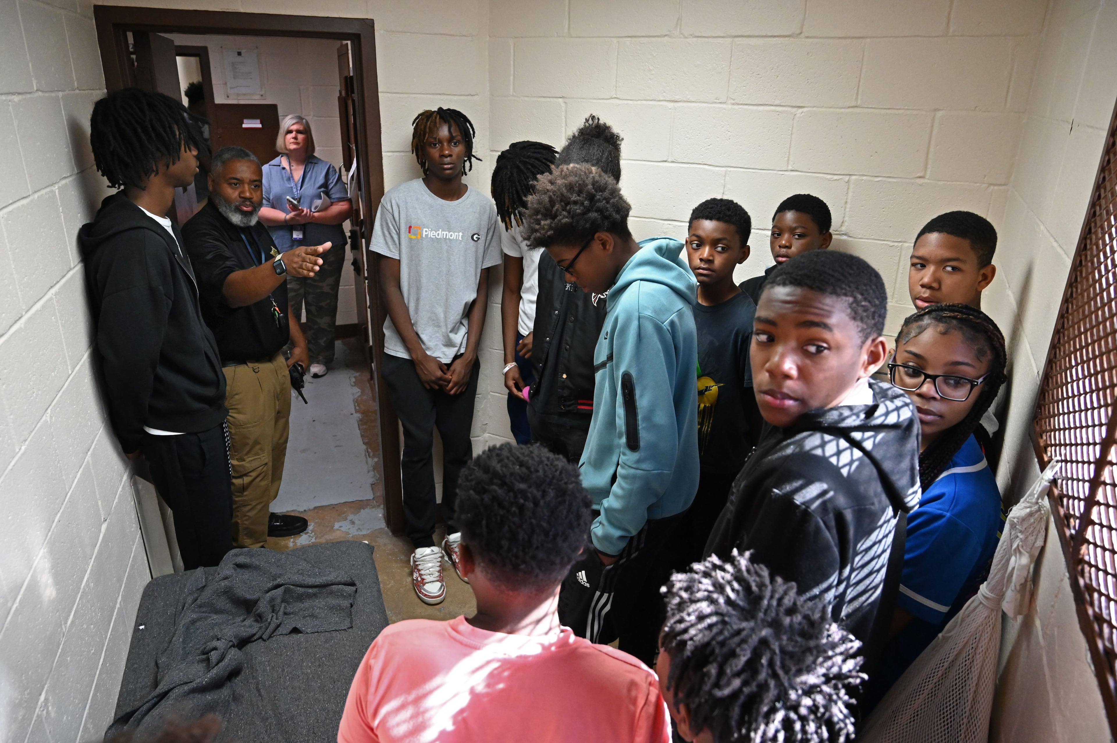 Sgt. Andre Greene (back left) shows an Athens-Clarke County Correctional Institution isolation unit to students touring as part of the Beyond the Bars program. "This is not where you want to be," he told them. (Hyosub Shin/AJC)