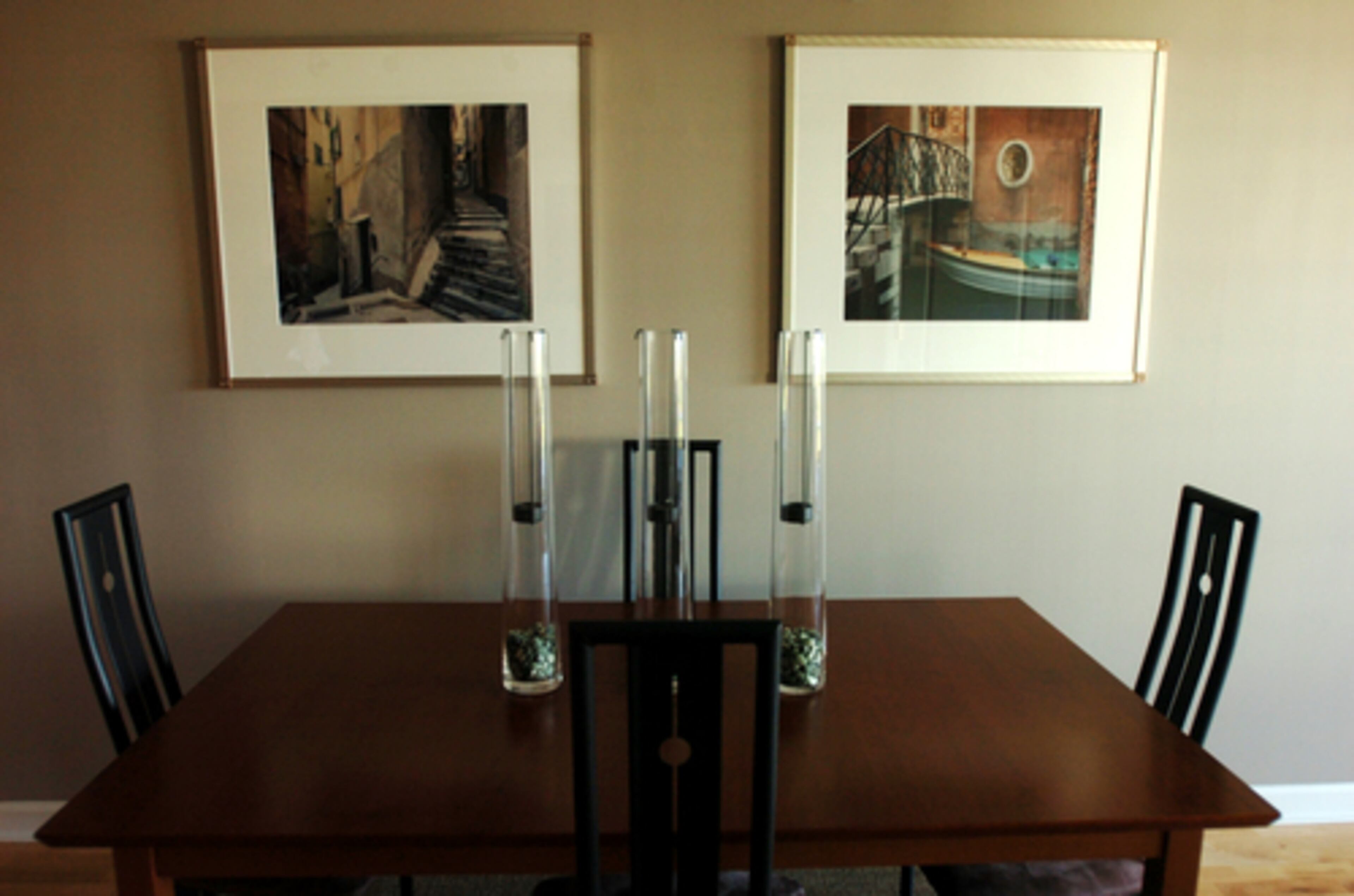 The dining area's artworks are photos of Venice hanging above the rectangular table which is lined with sleek, narrow-back chairs.