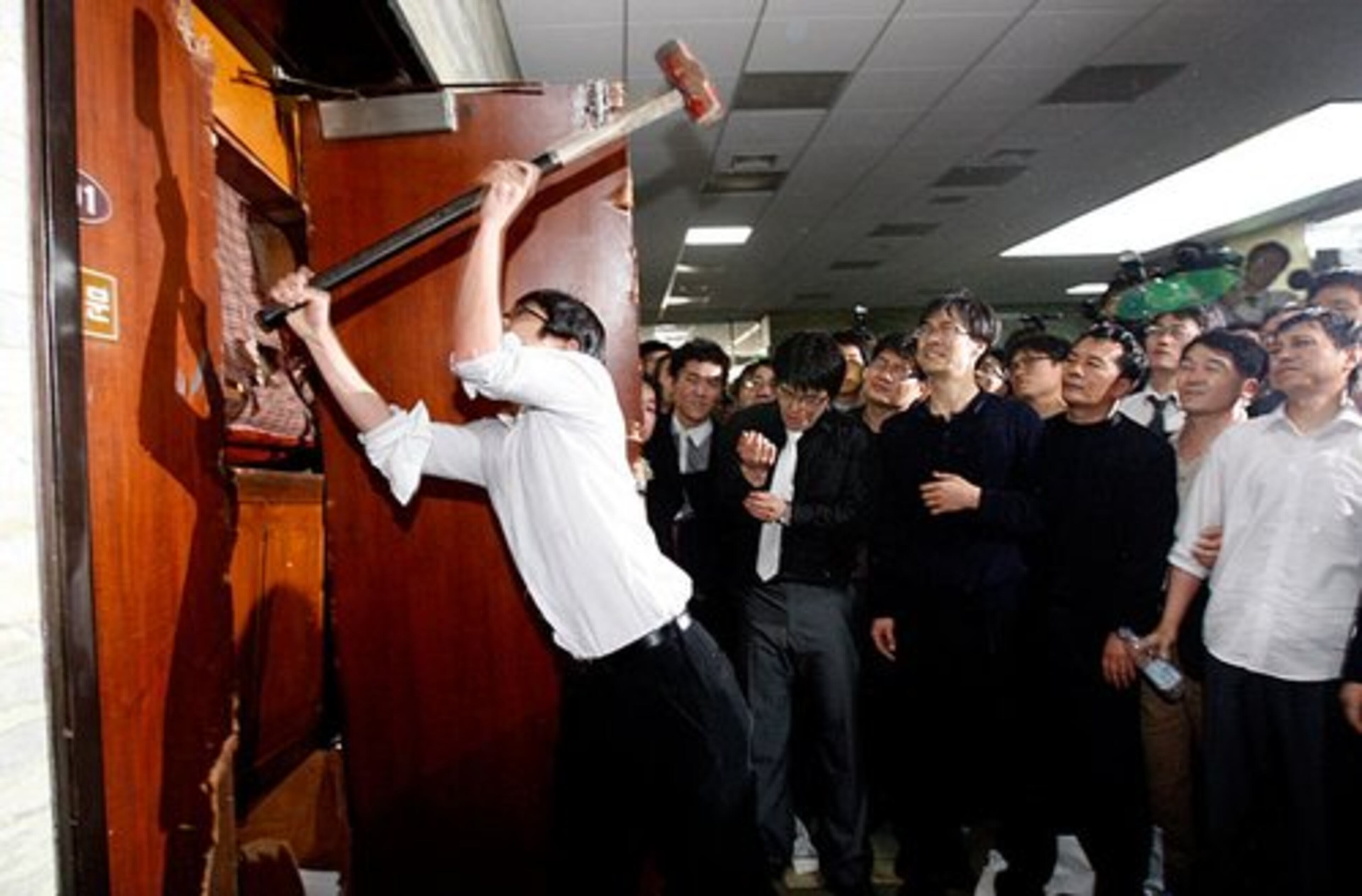 An opposition party member uses a hammer beat down a door leading to a parliamentary committee room.