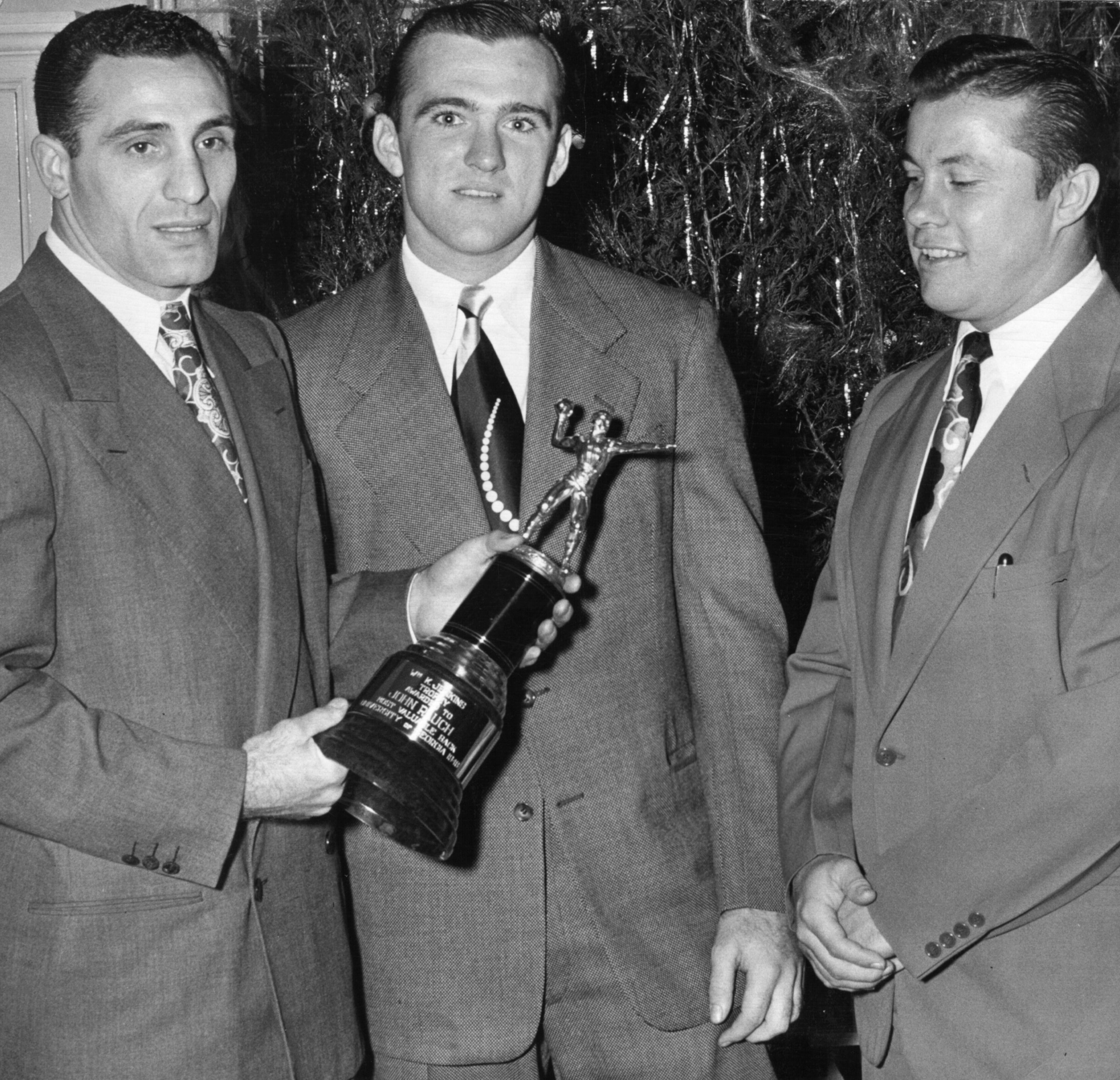 Georgia's All-Americans: Former All-American Charlie Trippi (left) and Frankie Sinkwich (right) present the William K. Jenkins Trophy to 1948 All-American Johnny Rauch. This was the third time Rauch received this trophy, honoring the Bulldogs' most outstanding player of the season.