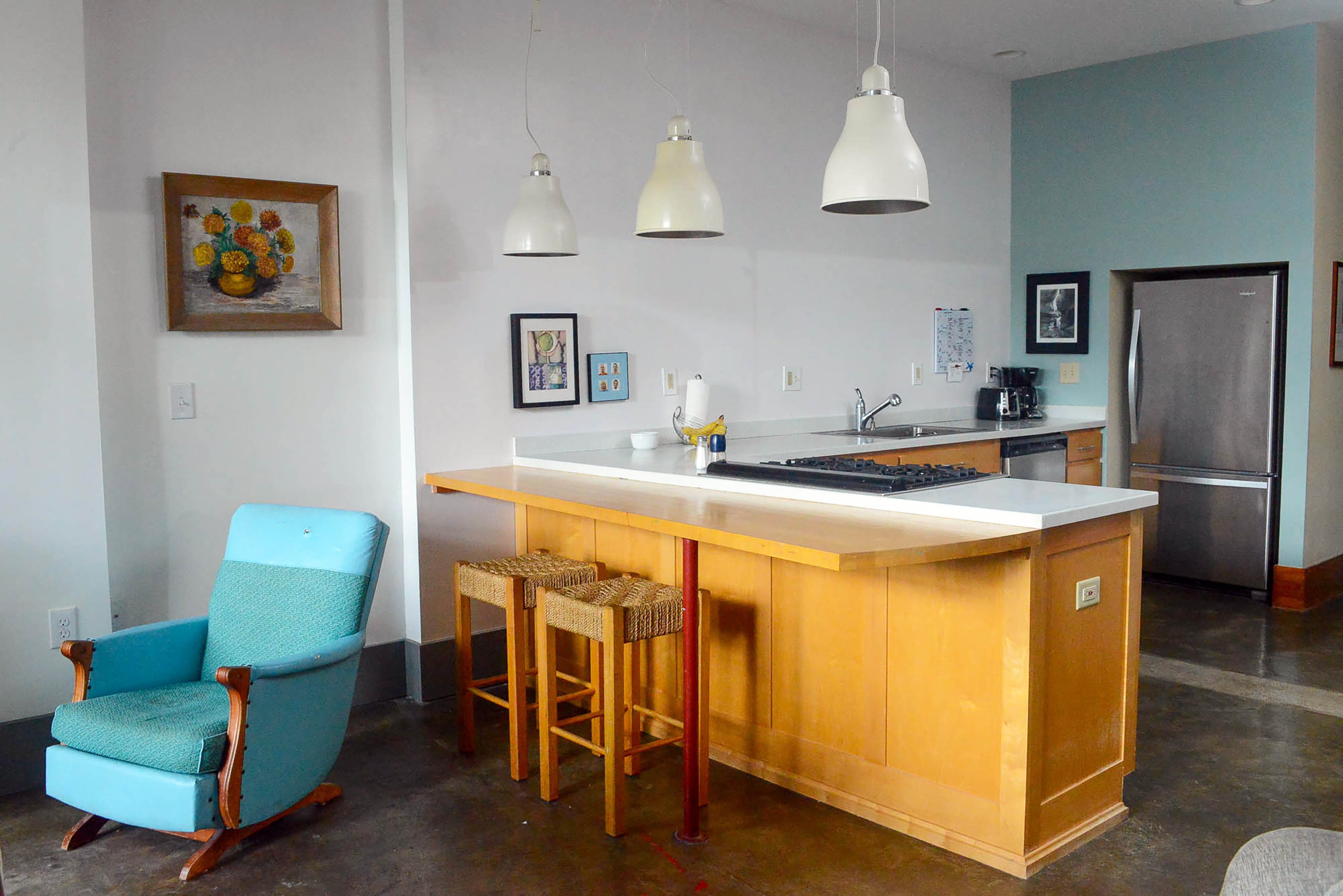 Large, white industrial pendant lights hang over the stovetop in the kitchen.