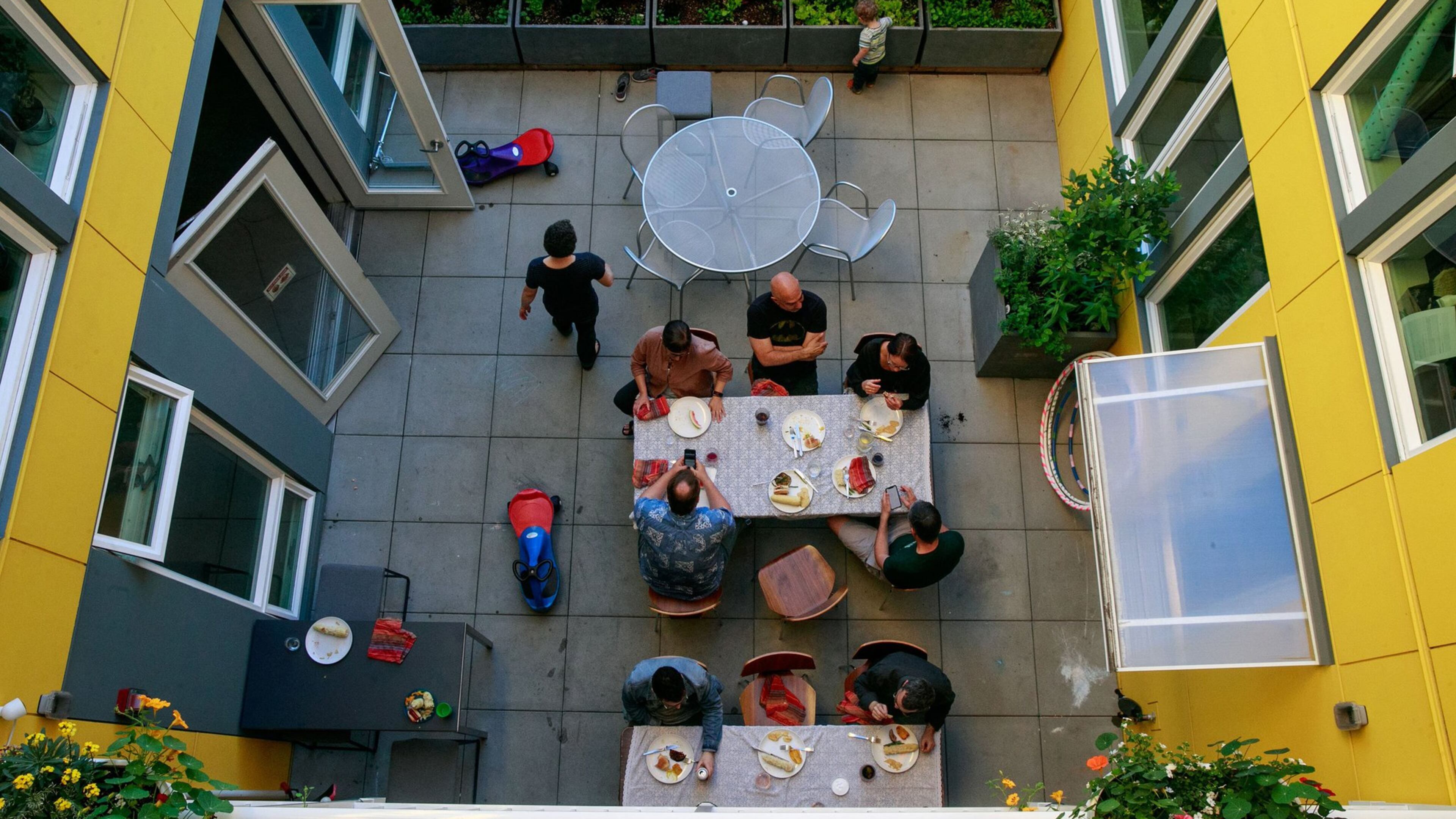 Residents of Capitol Hill Urban Cohousing talk over dinner in the central courtyard. We designed the building so all homes face the courtyard, says architect Grace Kim, who lives here with her family. When we were studying cohousing in Denmark, in general, Danish courtyards are in the center, so you d have shared outdoor space. Often the inside is a yellow/warm color. In the Pacific Northwest, it s really gray. Our concern was for light; it s nice to reflect happy yellow. Yellow goes through the common spaces. (Erika Schultz/The Seattle Times/TNS)