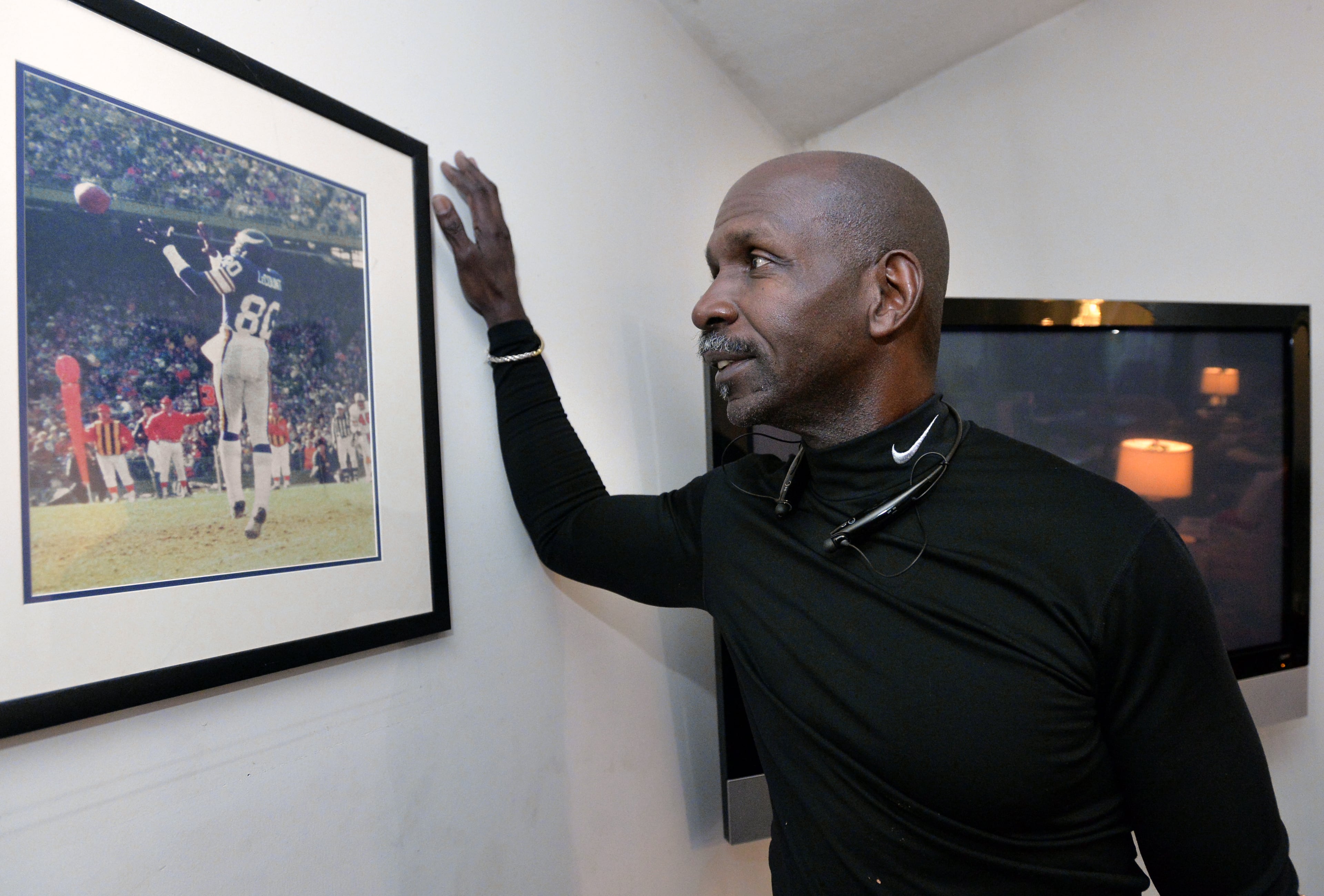 Former NFL player Terry LeCount smiles as he looks at a photo from his years as an NFL player at his home in Riverdale. LeCount struggled with addiction but went on to spend a decade as a paraprofessional at Oakhurst Elementary School in Decatur where he became a mentor to many. He now works at the College Football Hall of Fame. HYOSUB SHIN / HSHIN@AJC.COM