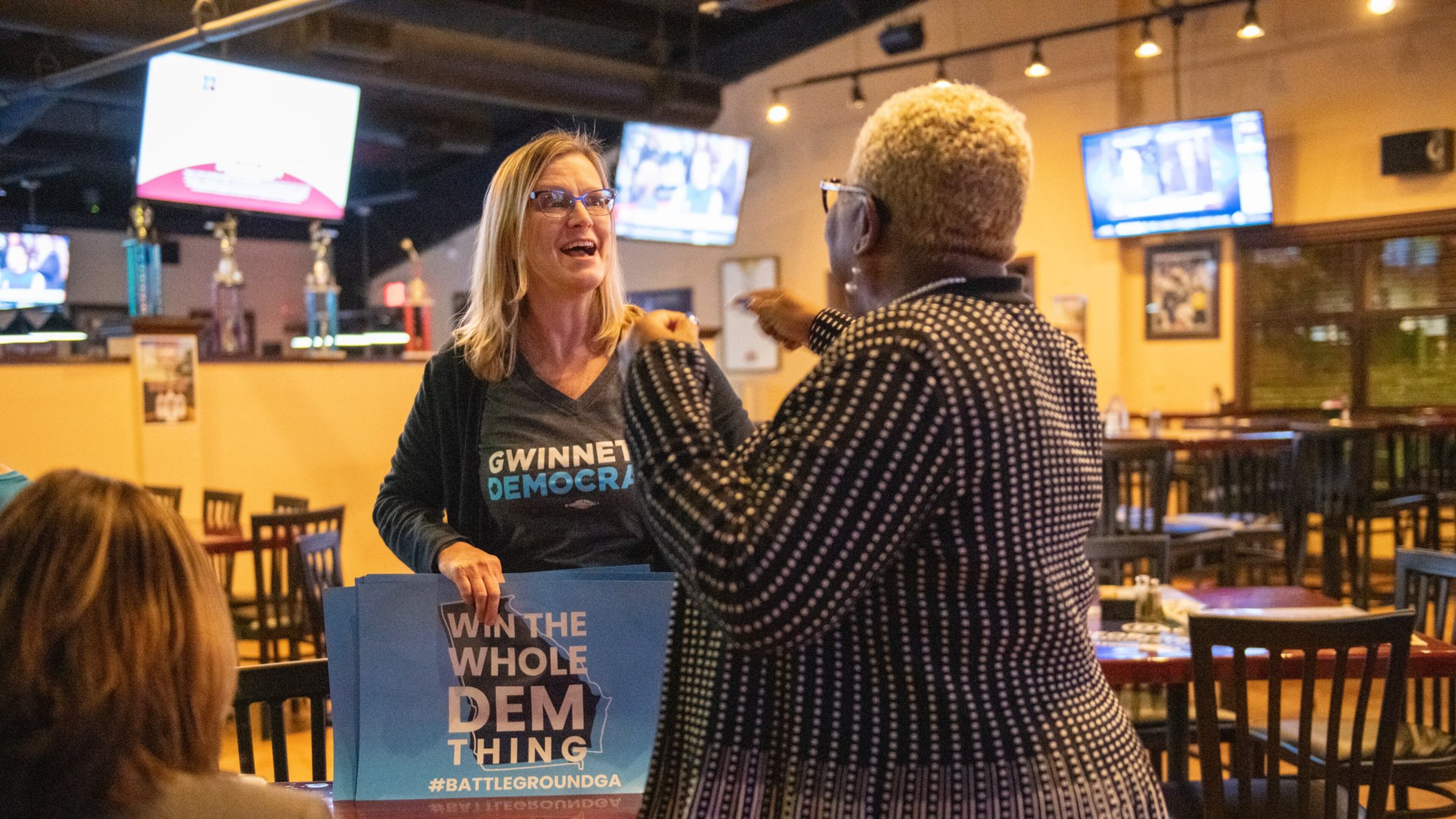 111419 NORCROSS— From left, Penny Bernath, Chair of Campaign Elections, greets Pinkie Farver, the District Director for the Georgia Federation of Democratic Women before they watch the presidential debates held in Atlanta Wednesday, November 20, 2019 at Mazzy’s Sports Bar in Norcross, Ga. PHOTO BY ELISSA BENZIE