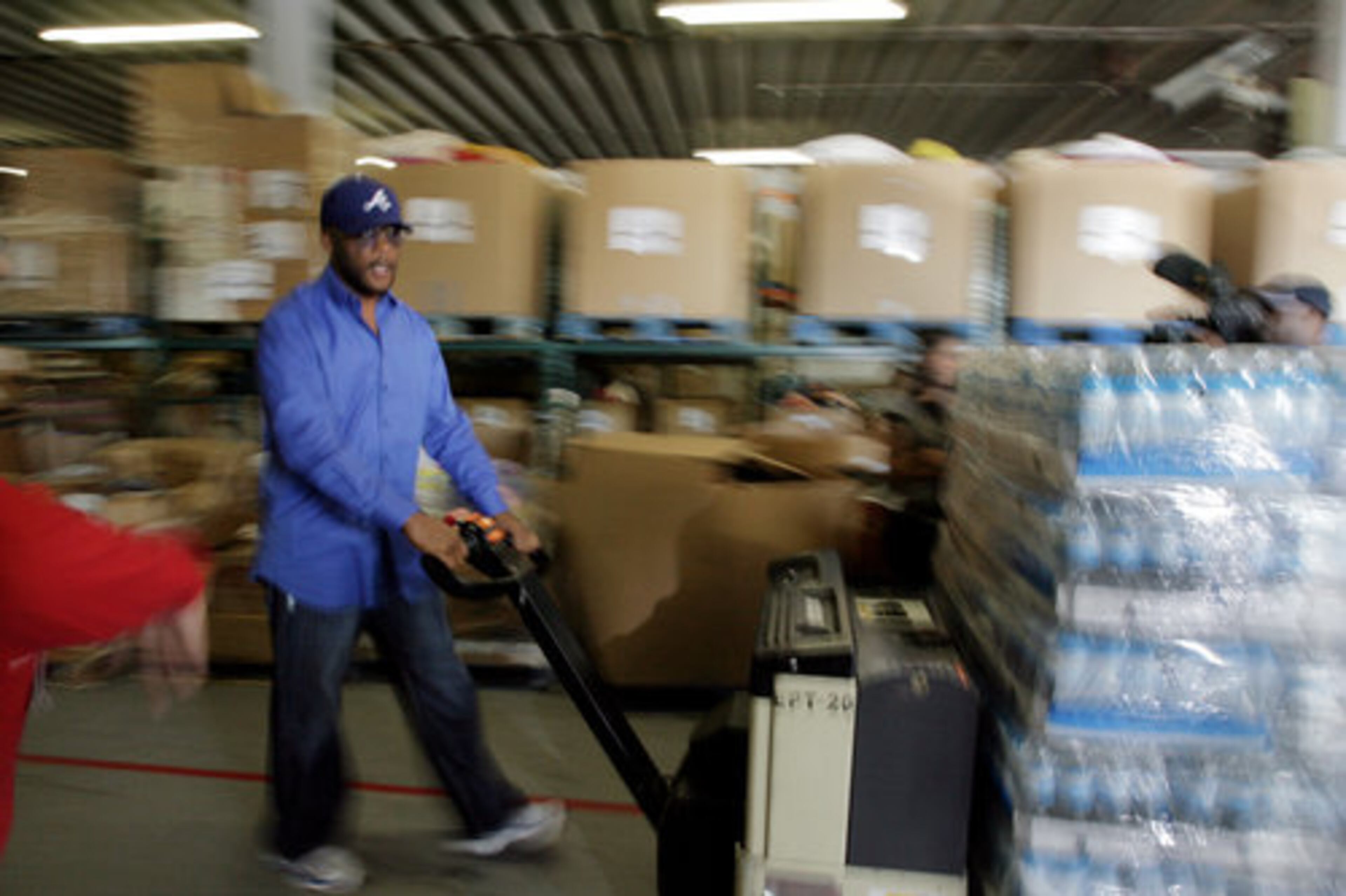 Perry joked with the assembled media pointing cameras at him as he maneuvered a large hydraulic hand truck loaded down with a pallet of spring water. The $50,000 worth of food will feed more than 1,000 families for two weeks.