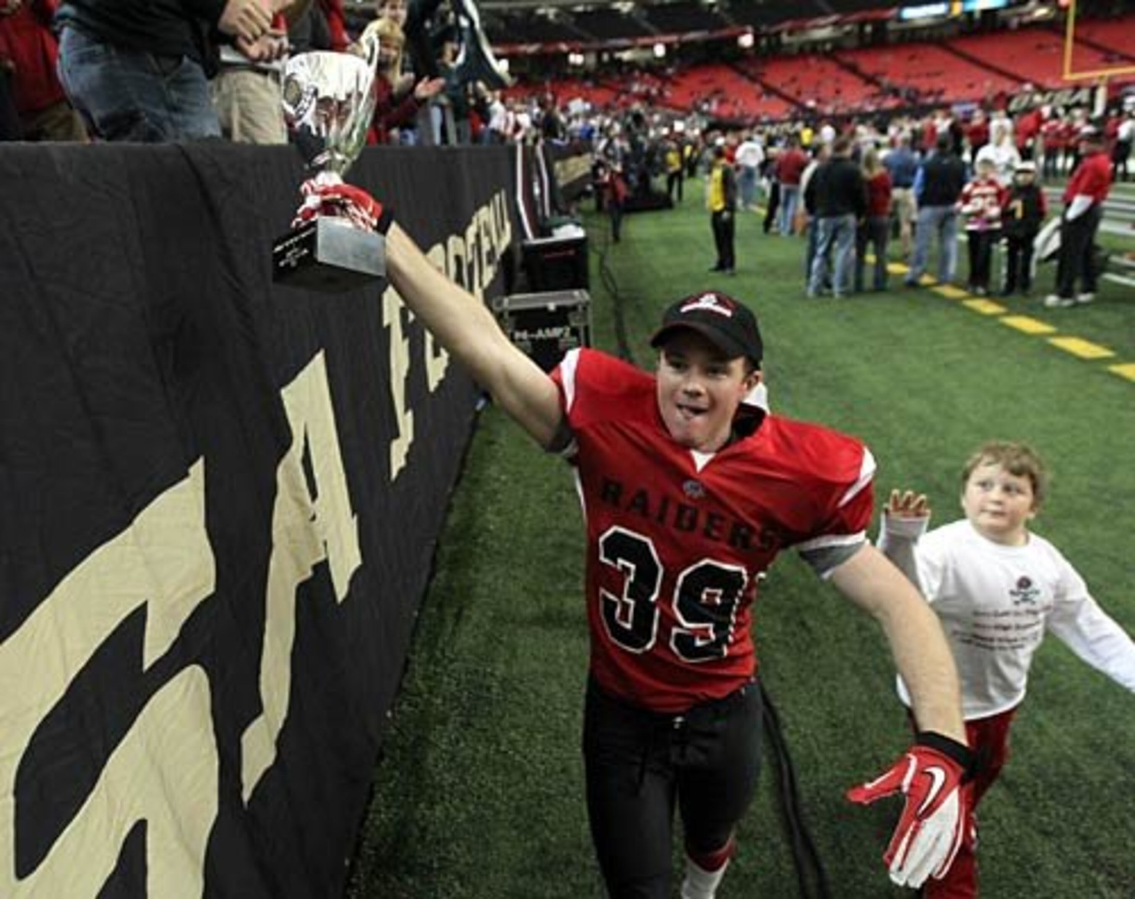 Savannah Christian defensive back Drew Davis shows the trophy to fans after Savannah Christian defeated Landmark Christian.