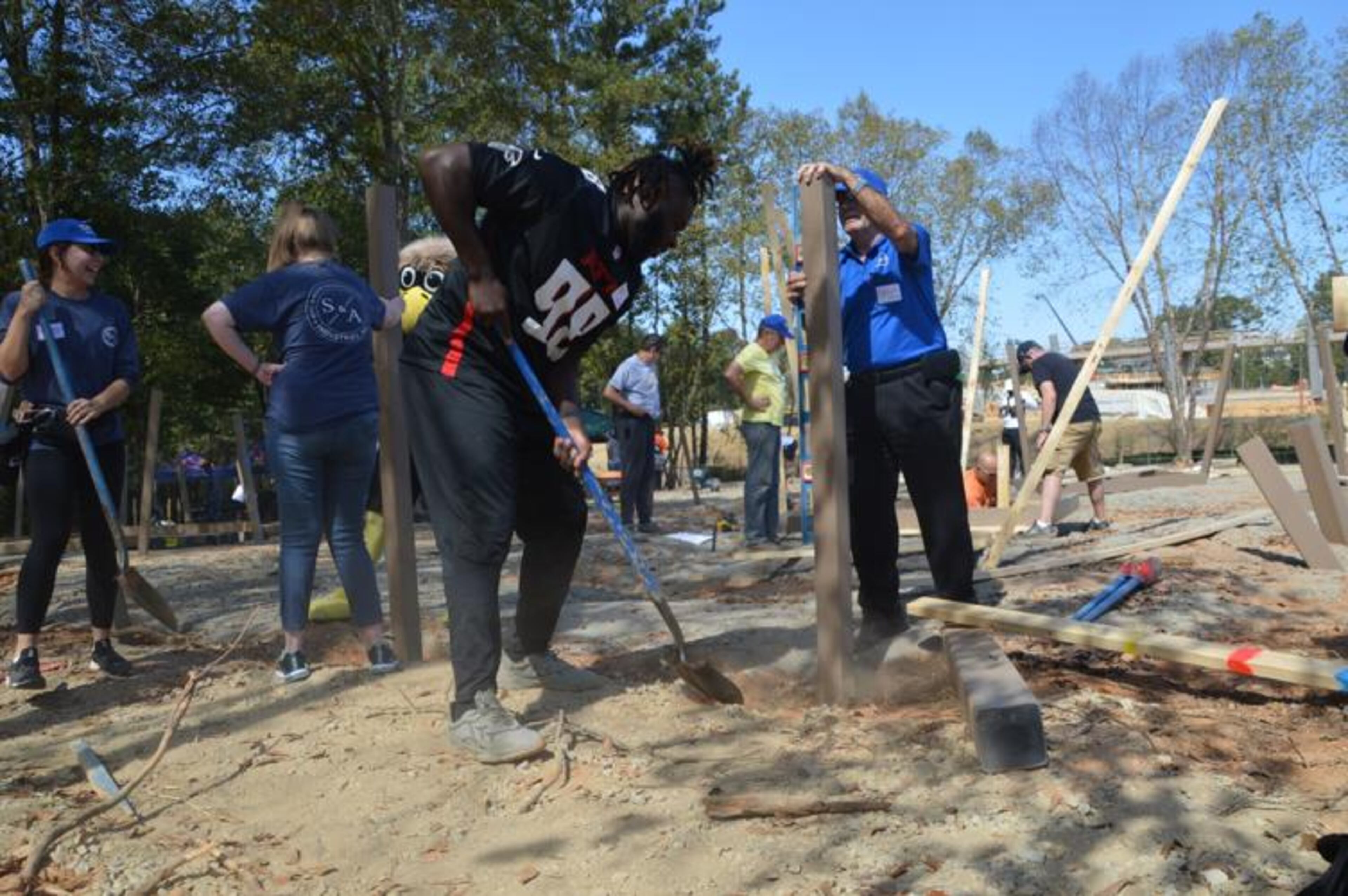 Atlanta Falcons defensive lineman Timmy Horne, center, helps shovel dirt with PlayTown Suwanee volunteers on Tuesday. Members of the Falcons organization volunteered to help build part of the playground at the Suwanee Town Center on Main park site. (Photo Courtesy of Curt Yeomans)