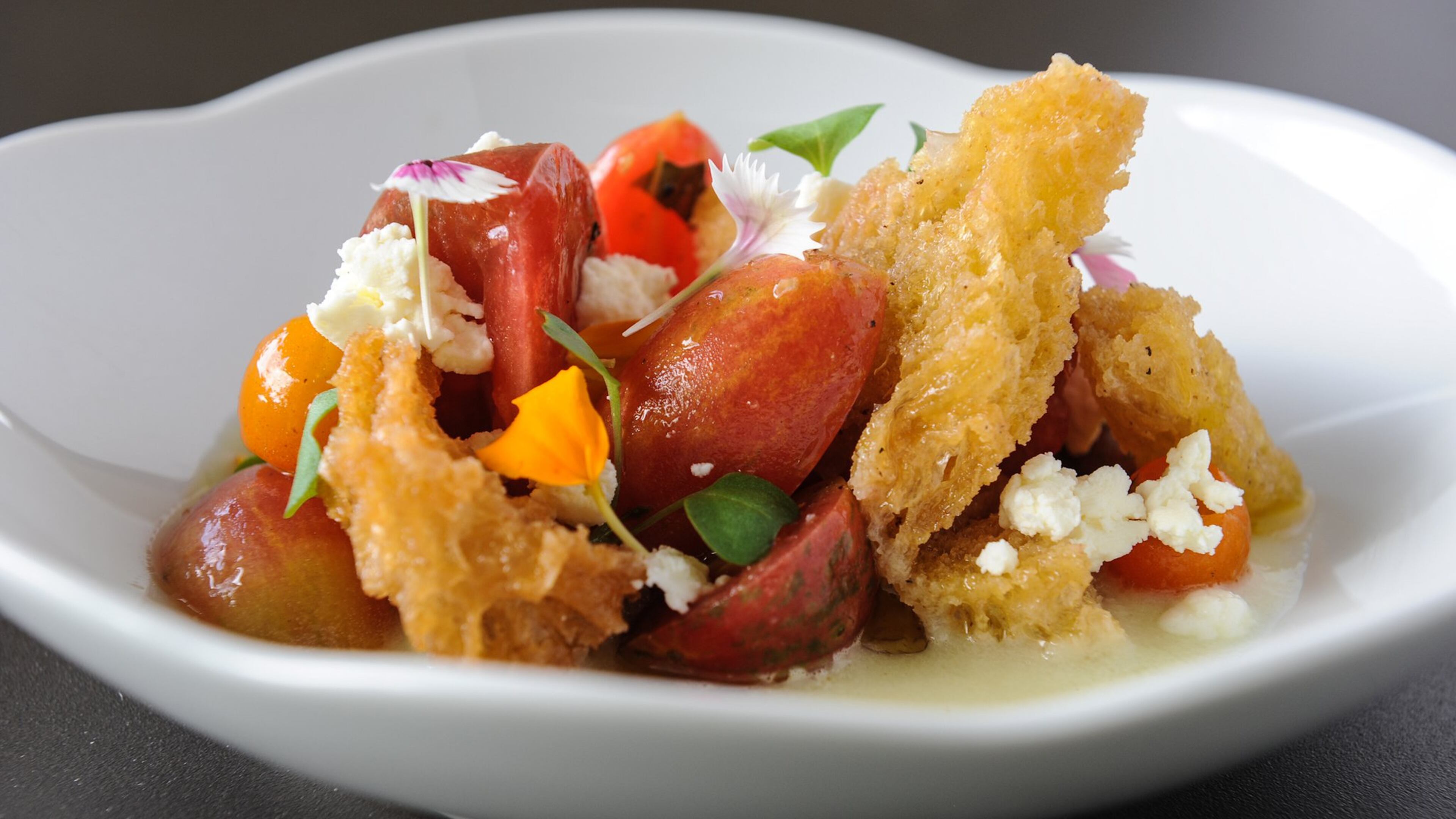 An heirloom tomato salad features cherry tomatoes, with chunks of fromage blanc, basil and croutons atop a thin coating of a cucumber gazpacho. (BECKY STEIN PHOTOGRAPHY)