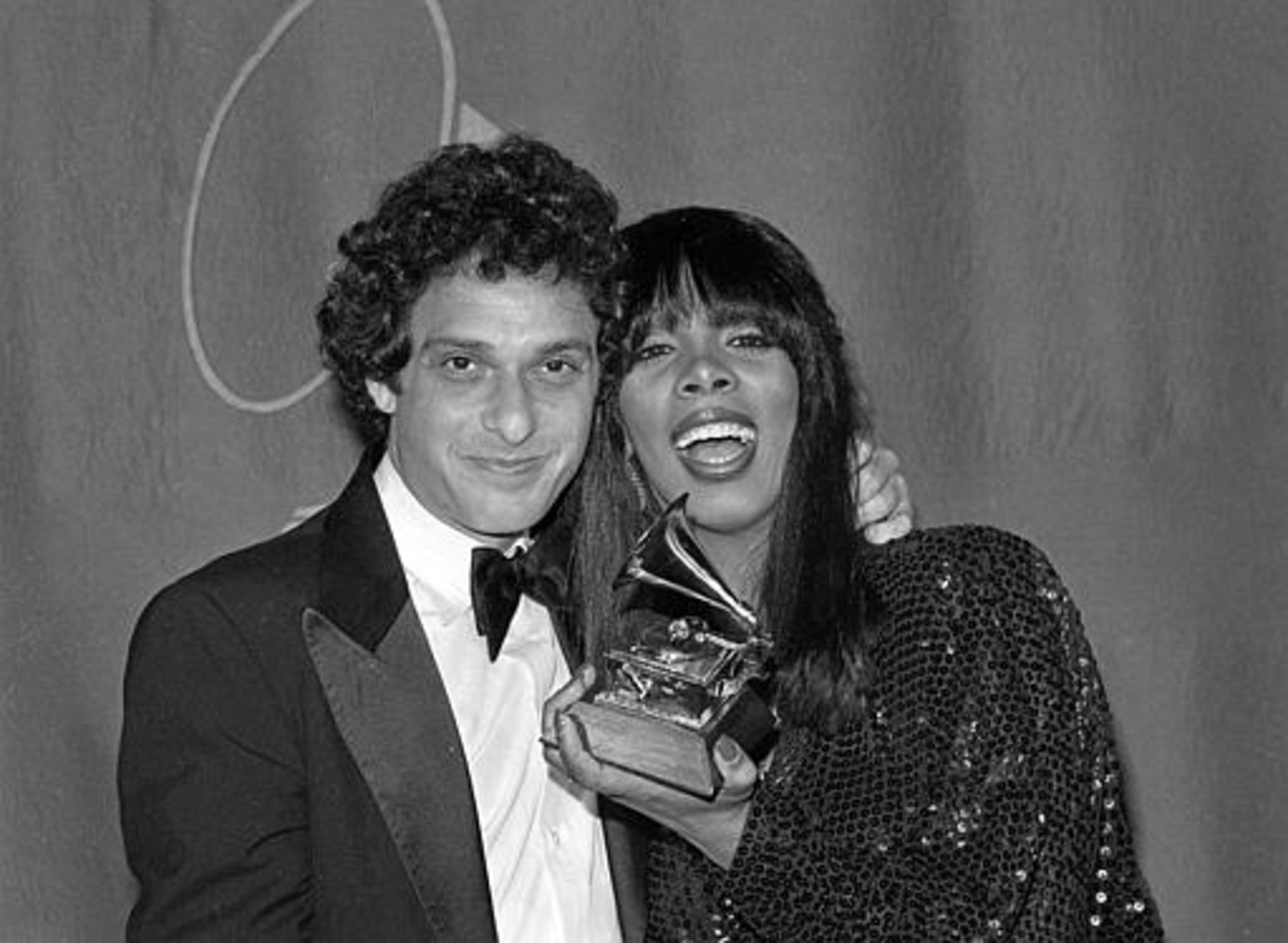 Singer Donna Summer, holding her Grammy, is embraced by composer Paul Jabara at the 21st annual Grammy Awards in Los Angeles, Ca., Feb. 15, 1979. Summer won top female rhythm and blues performer for "Last Dance" written by Jabara, who also won a Grammy for the same song for best instrumental composition. (AP Photo/Lennox McLendon)