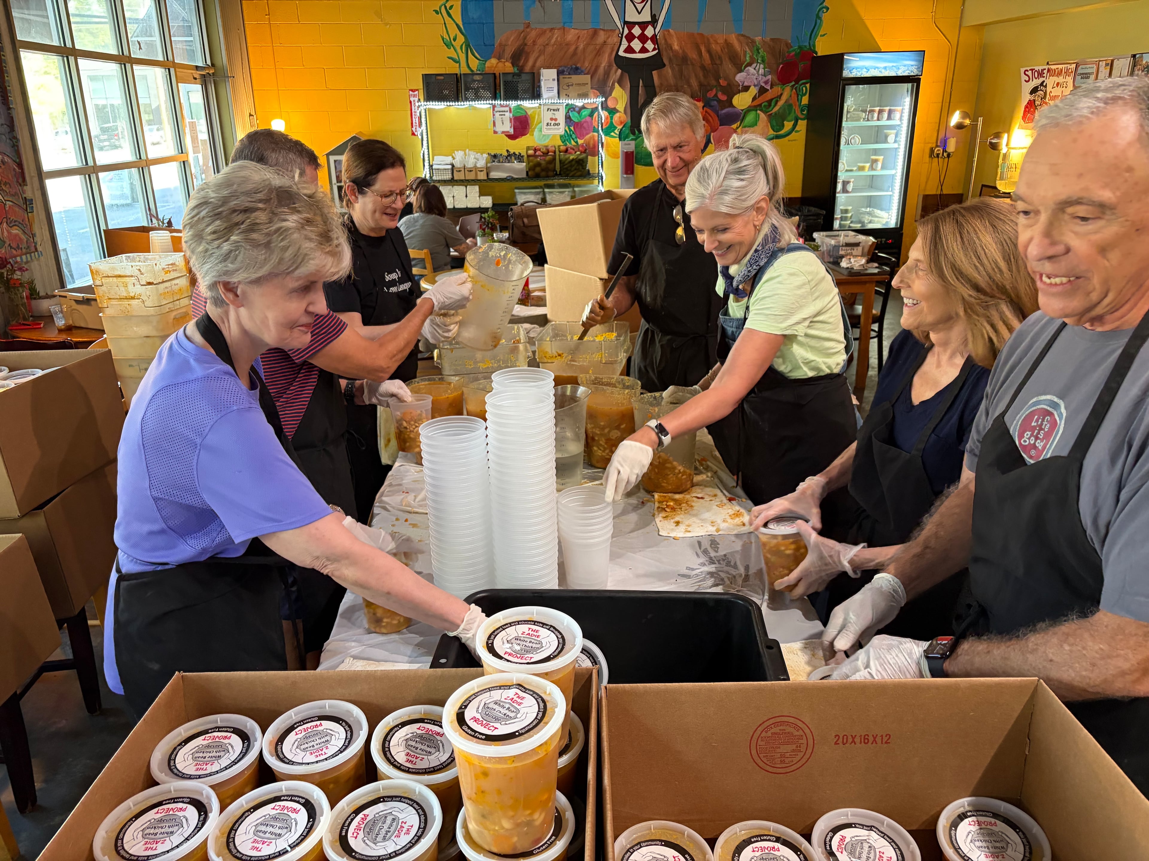 Volunteers prepare boxes of food for distribution at Souper Jenny’s for the Zadie Project, which distributes 1,000 quarts of soup to needy organizations across Atlanta every week. (Jason Armesto/AJC)