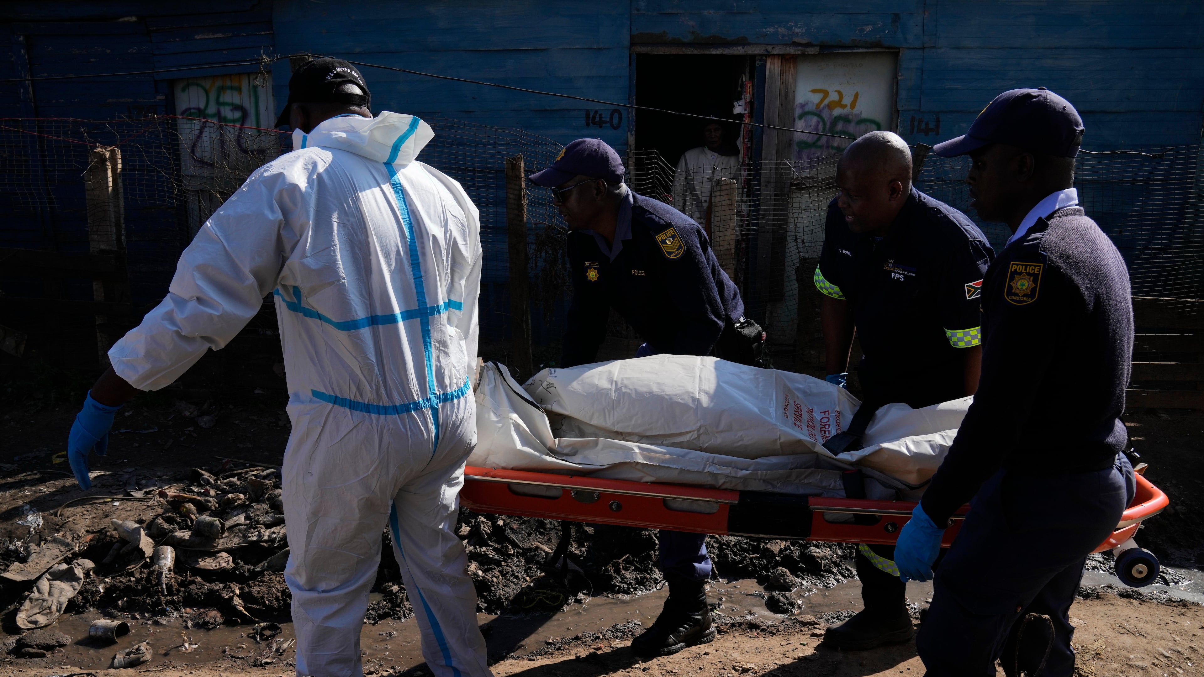 Police officers carry the body of a person on a stretcher after a mass shooting at an informal settlement in the Cleveland suburb of Johannesburg, South Africa, Wednesday, June 10, 2026. (AP Photo/Themba Hadebe)