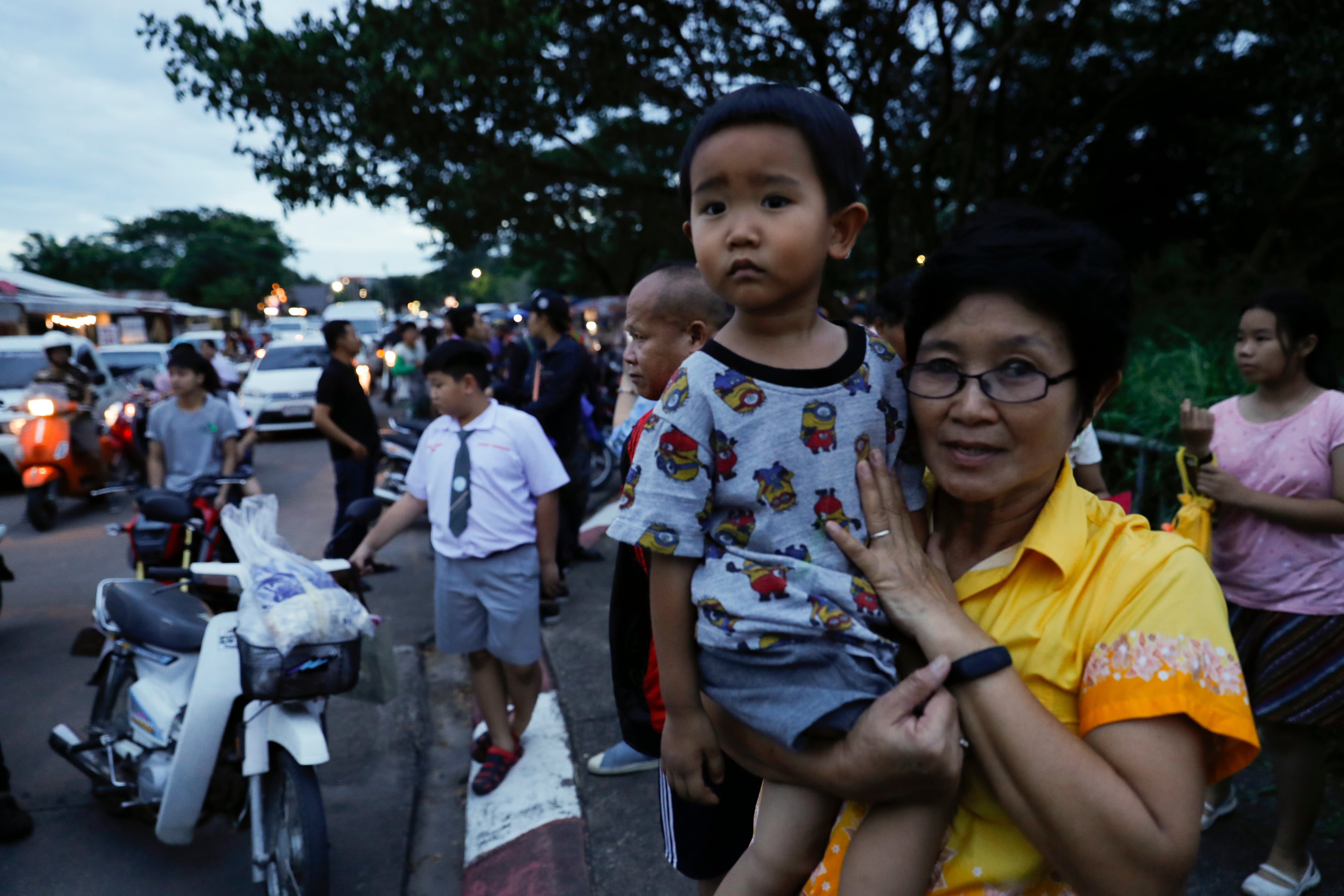 People wait as police block the road during an emergency helicopter evacuation in Chiang Rai as divers evacuated some of the 12 boys and their coach trapped at Tham Luang cave in the Mae Sai district of Chiang Rai province, northern Thailand, Tuesday, July 10, 2018. Thai Navy SEALs say all 12 boys and their coach were rescued from the cave, ending an ordeal that lasted more than 2 weeks. (AP Photo/Vincent Thian)