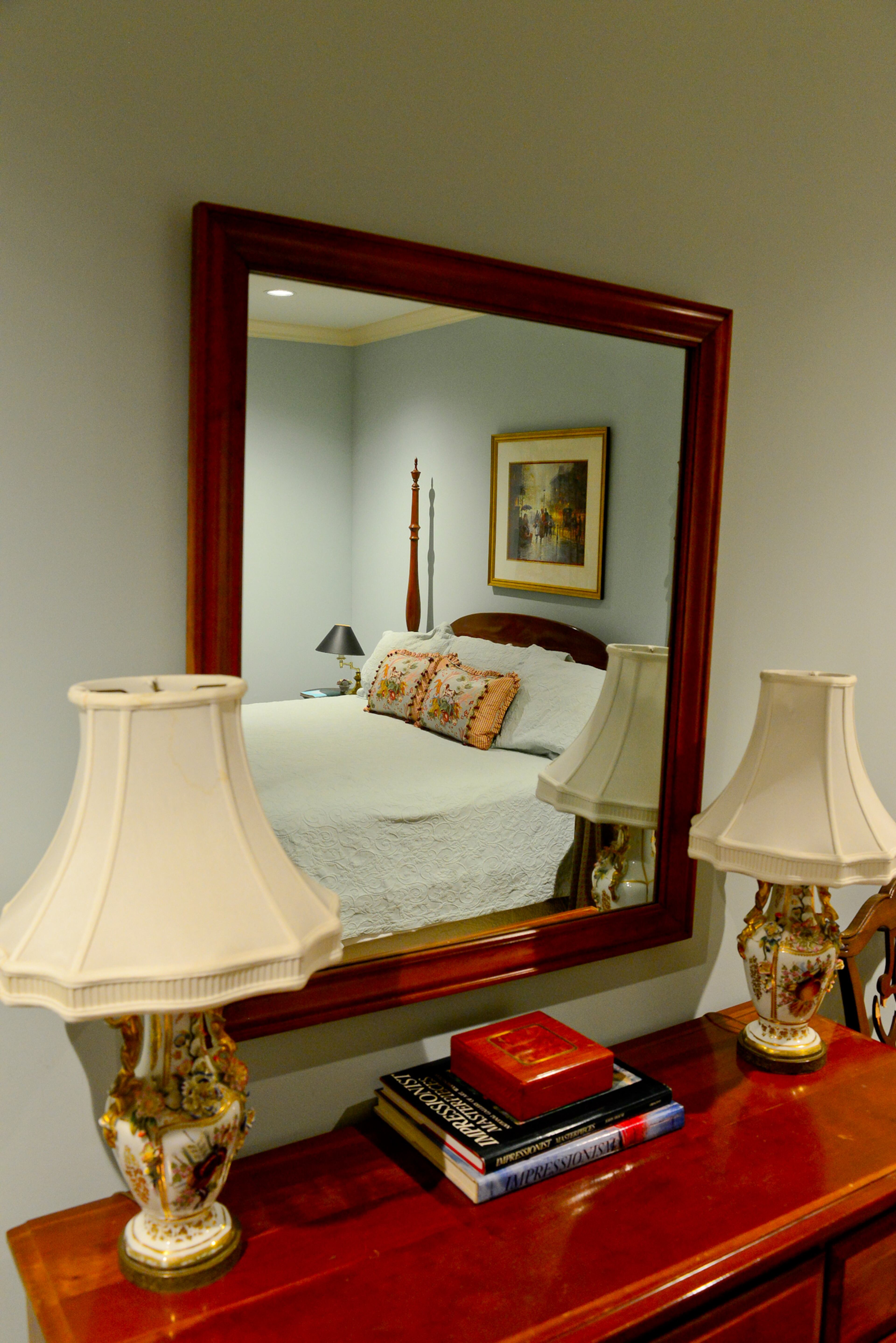 In the guest room, the bed, bedding, chest, art and table lamps fit with the home's French Country design.