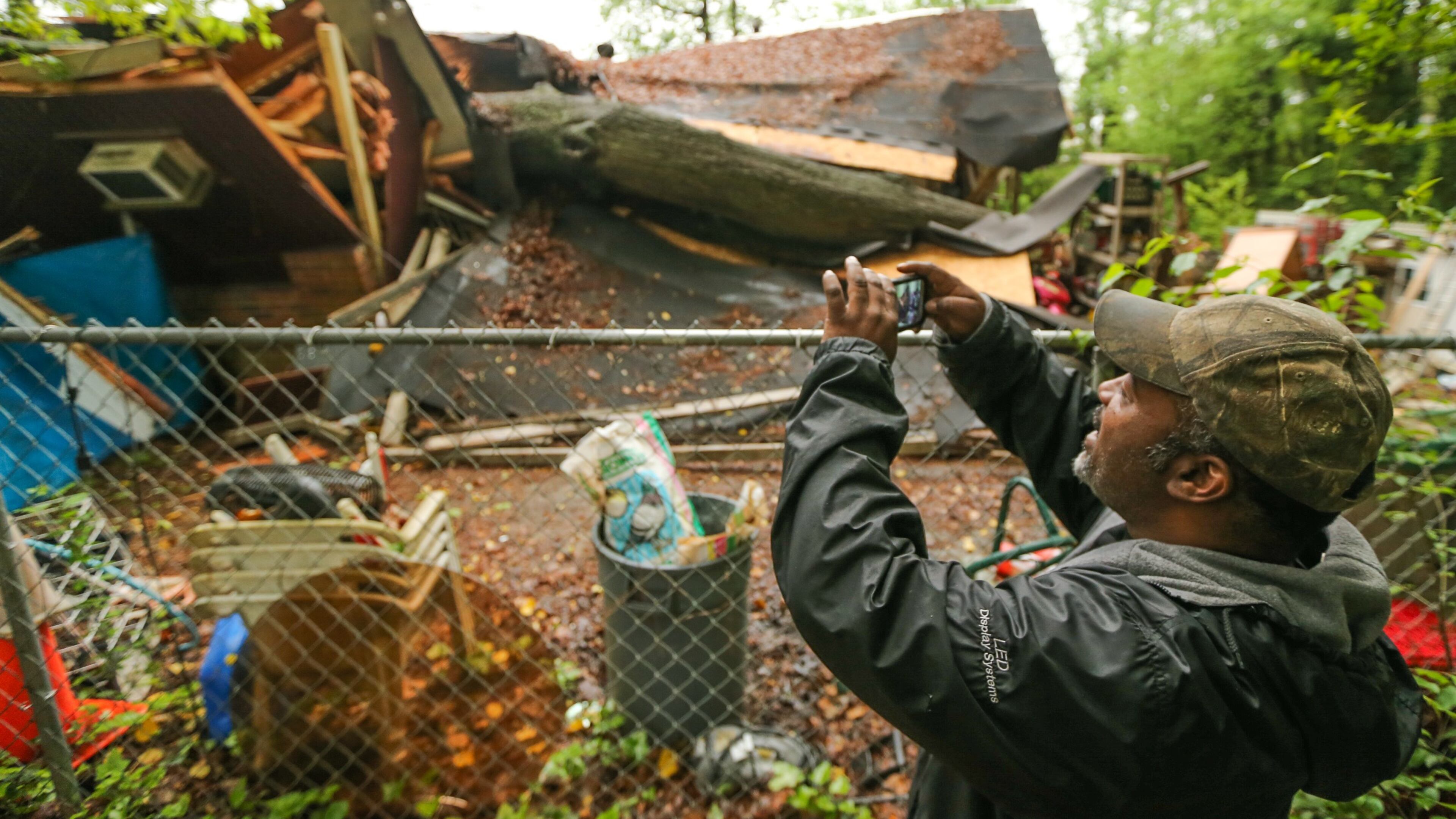 Damon Sylve takes photos of the tree that crashed down onto his family’s southwest Atlanta home early Friday. JOHN SPINK / JSPINK@AJC.COM