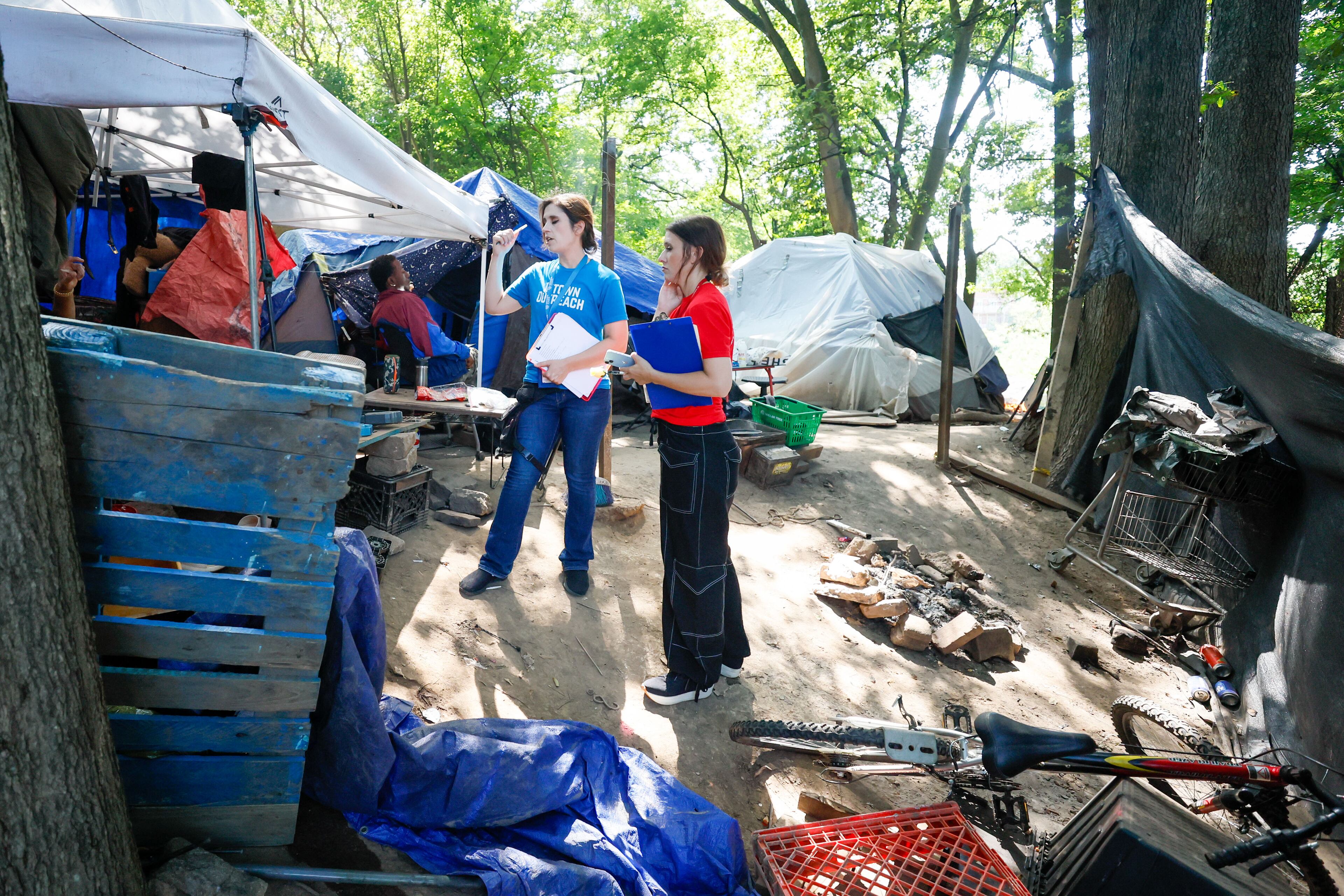 Tracy Woodard from Intown Cares (left) and Lauren Hopper from Mercy Care speak with a resident of the Cooper Street encampment, which closed in October. Woodard led a team of people who conducted surveys for this year’s point-in-time count. (Miguel Martinez/AJC 2024)