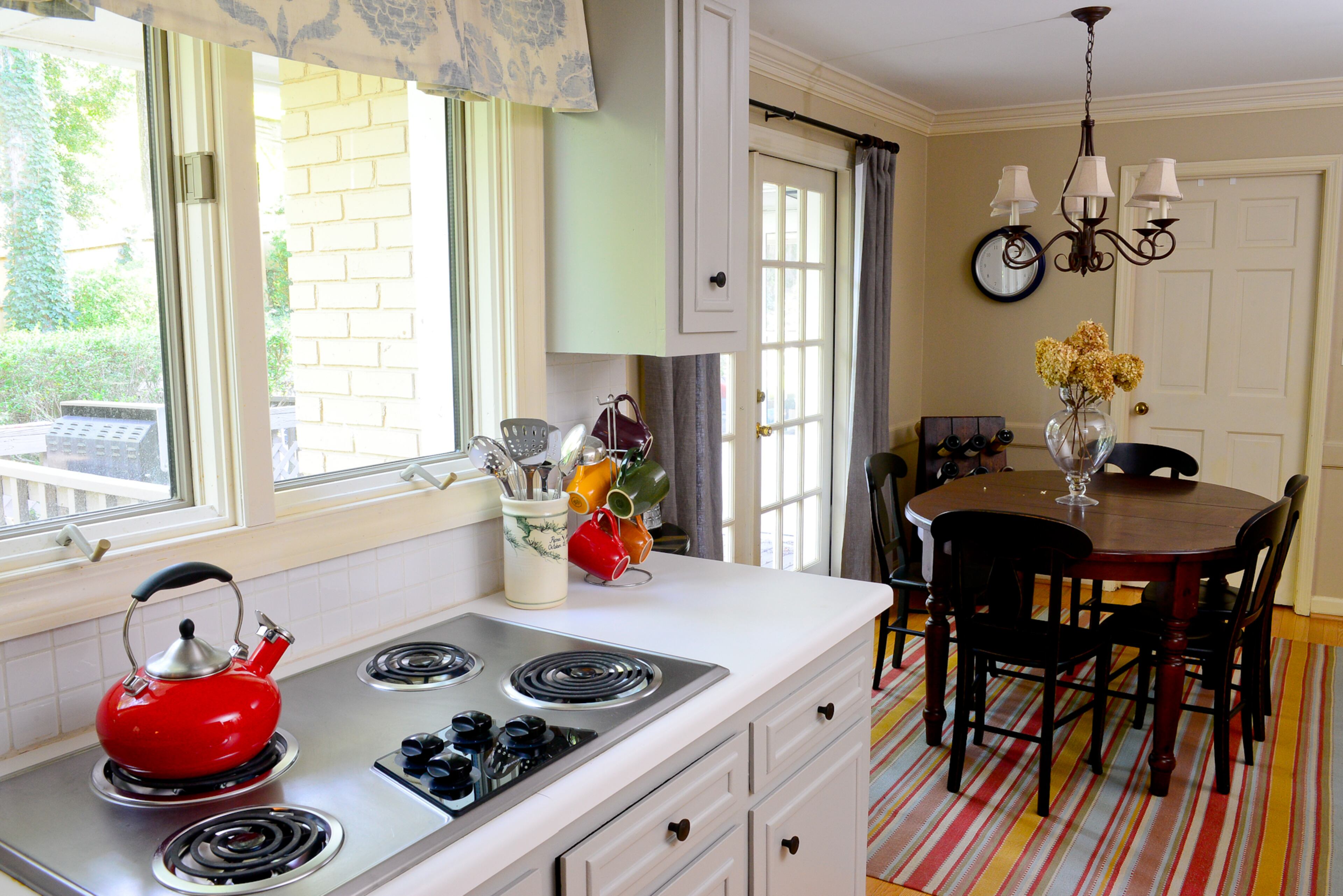 The kitchen and dining area are open to each other, flowing out onto the deck. The striped rug is by Dash & Albert, with custom window treatments by Lauren Harris Interiors.
