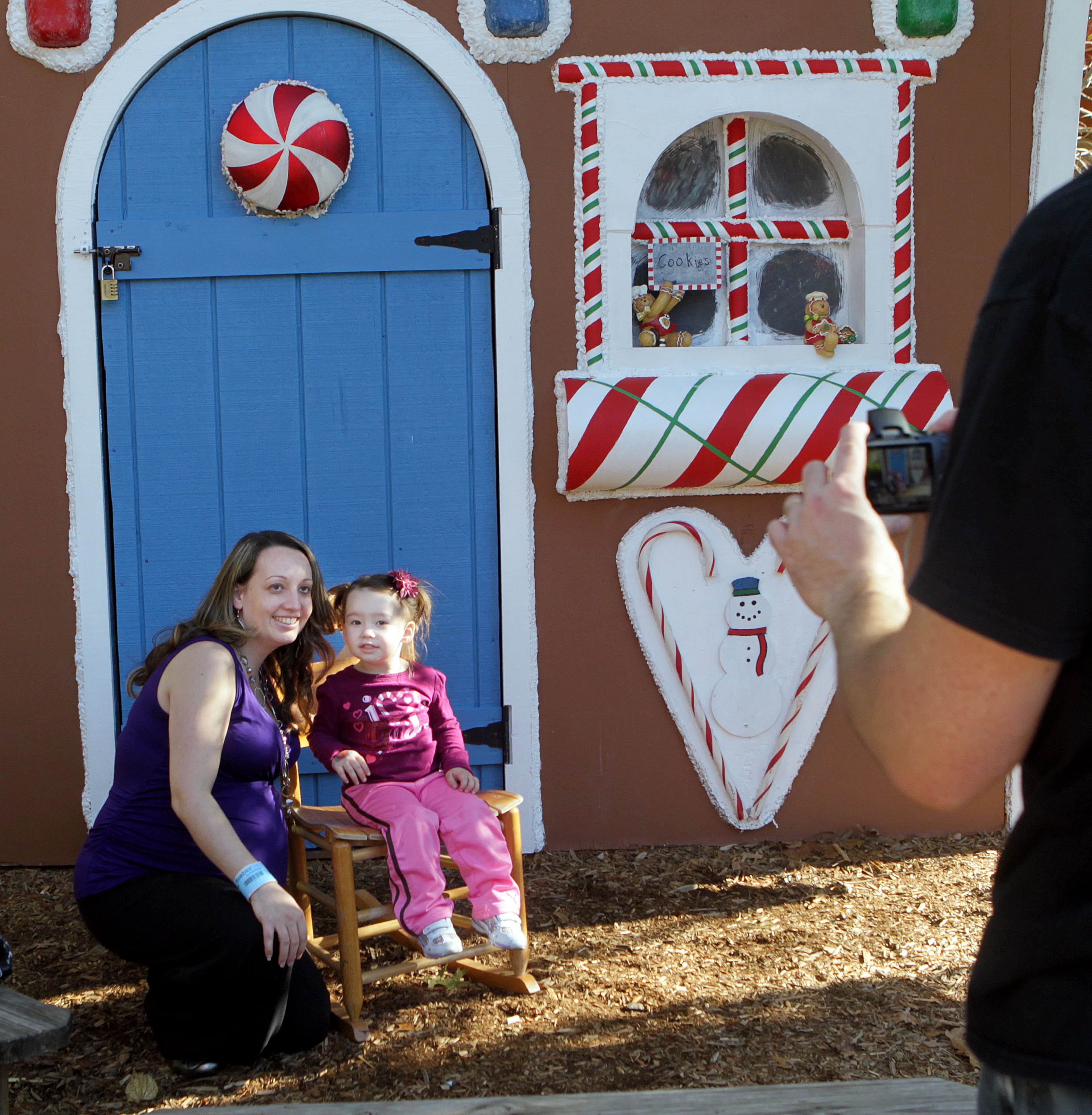 Elizabeth Jamison (left) and her 2-year-old daughter Liliana get their photo taken by Elizabeth's husband Robert in front of a gingerbread house at Stone Mountain Christmas at Crossroads ,located at the base of Stone Mountain on Saturday, Nov. 10, 2012. The Crossroads area is decked out with more than two million lights and features live holiday shows. Snow Mountain at Stone Mountain Park opens Nov. 19. Stone Mountain Christmas continues through Dec. 31.
