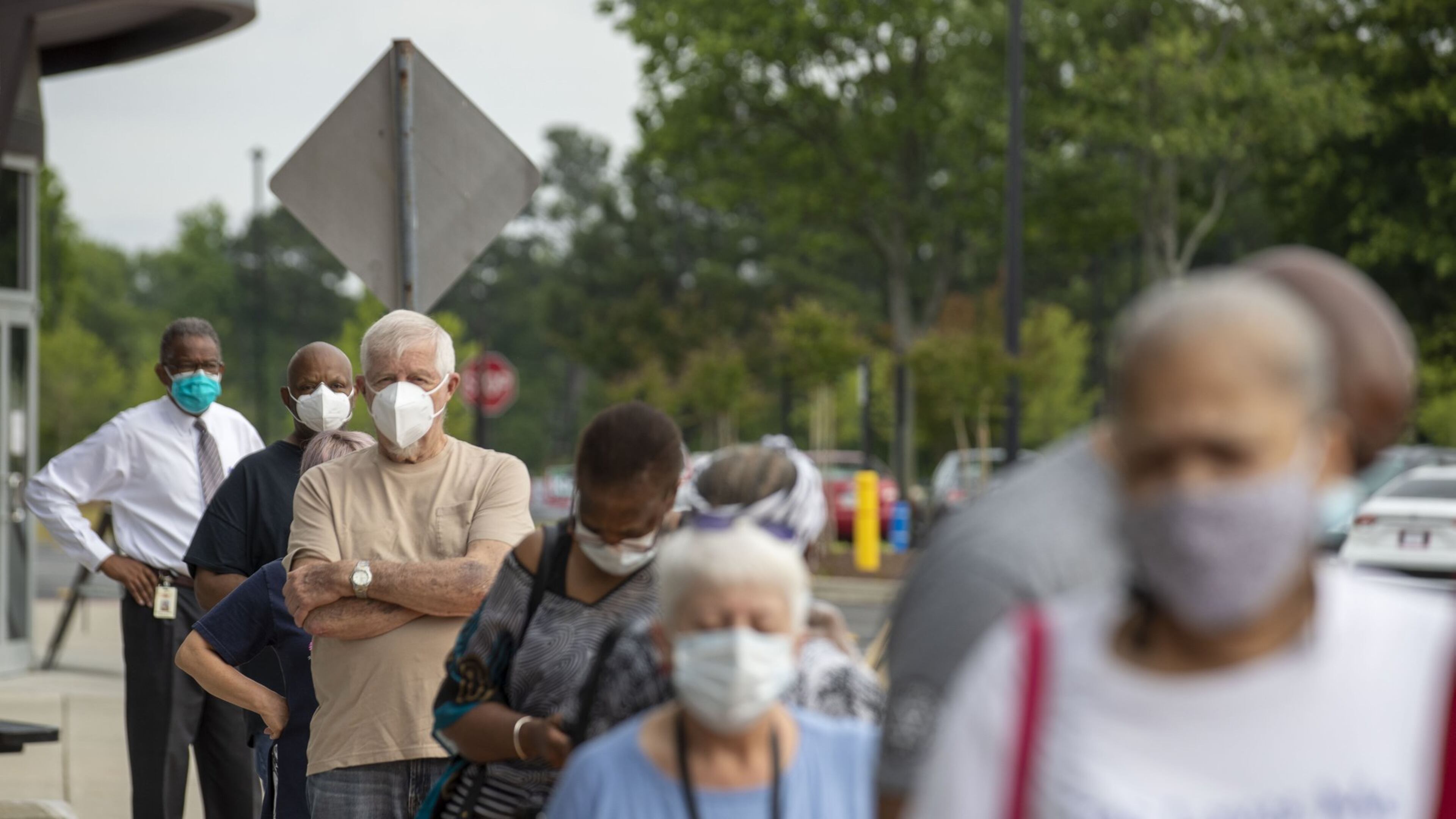 Voters wearing face masks stand in line outside the Gwinnett County Voter Registration and Elections Office in order to participate in early voting Monday in Lawrenceville. Early voting for the Georgia primary began Monday and will last three-weeks until June 5. Election day for the primary is June 9. (ALYSSA POINTER / ALYSSA.POINTER@AJC.COM)