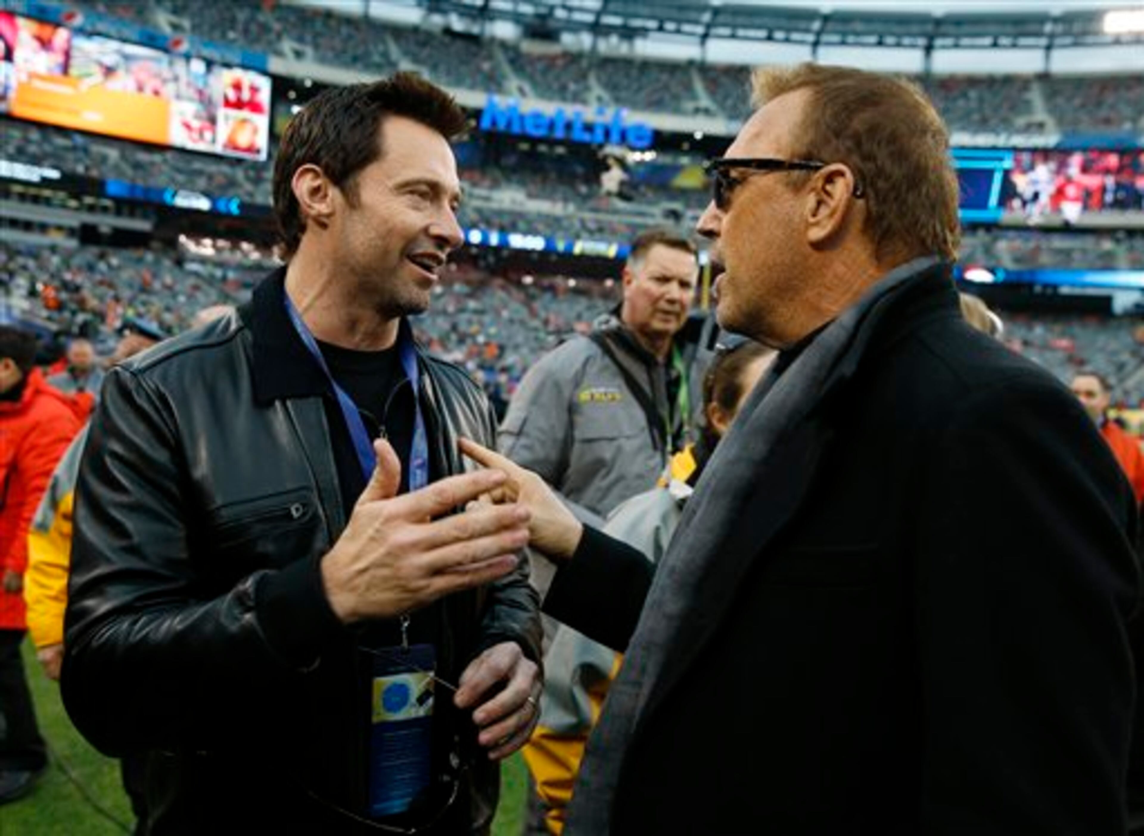 Actor Hugh Jackman, left, talks with fellow actor Kevin Costner, on the field before the NFL Super Bowl XLVIII football game between the Seattle Seahawks and the Denver Broncos Sunday, Feb. 2, 2014, in East Rutherford, N.J. (AP Photo/Evan Vucci)