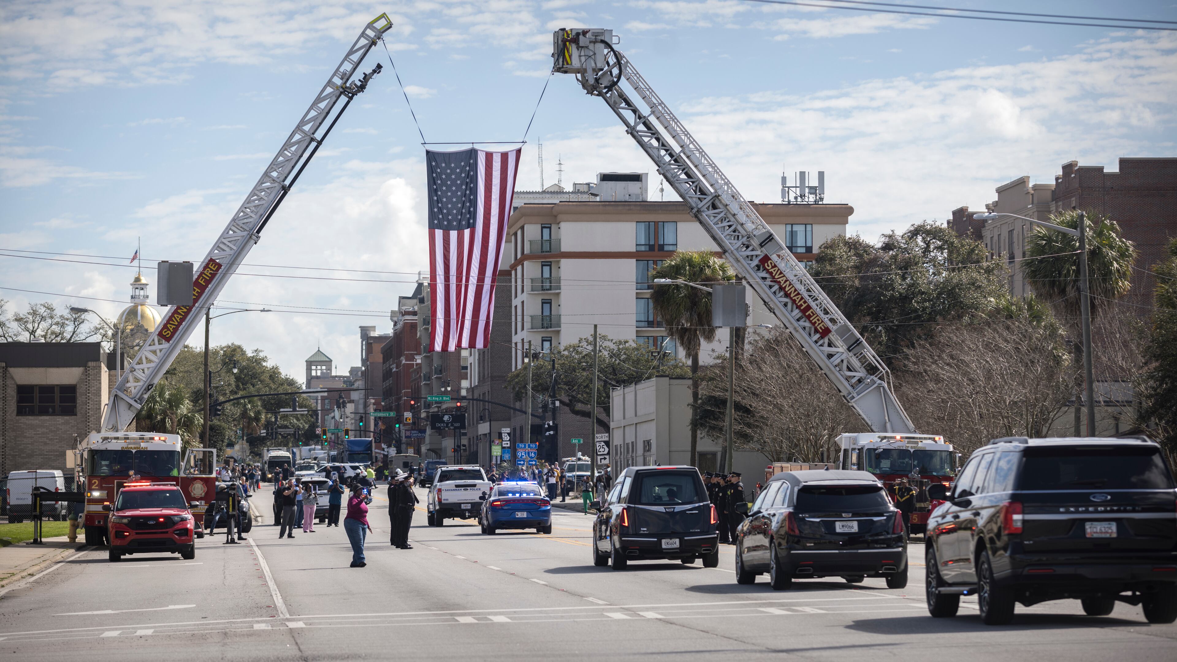 The hearse carrying remains of U.S. Army Reservist Sgt. Breonna Moffett, drives under a large American flag and members of the Savannah Fire Department during a motorcade procession, Thursday, Feb. 15, 2024, Savannah, Ga.. (AJC Photo/Stephen B. Morton)