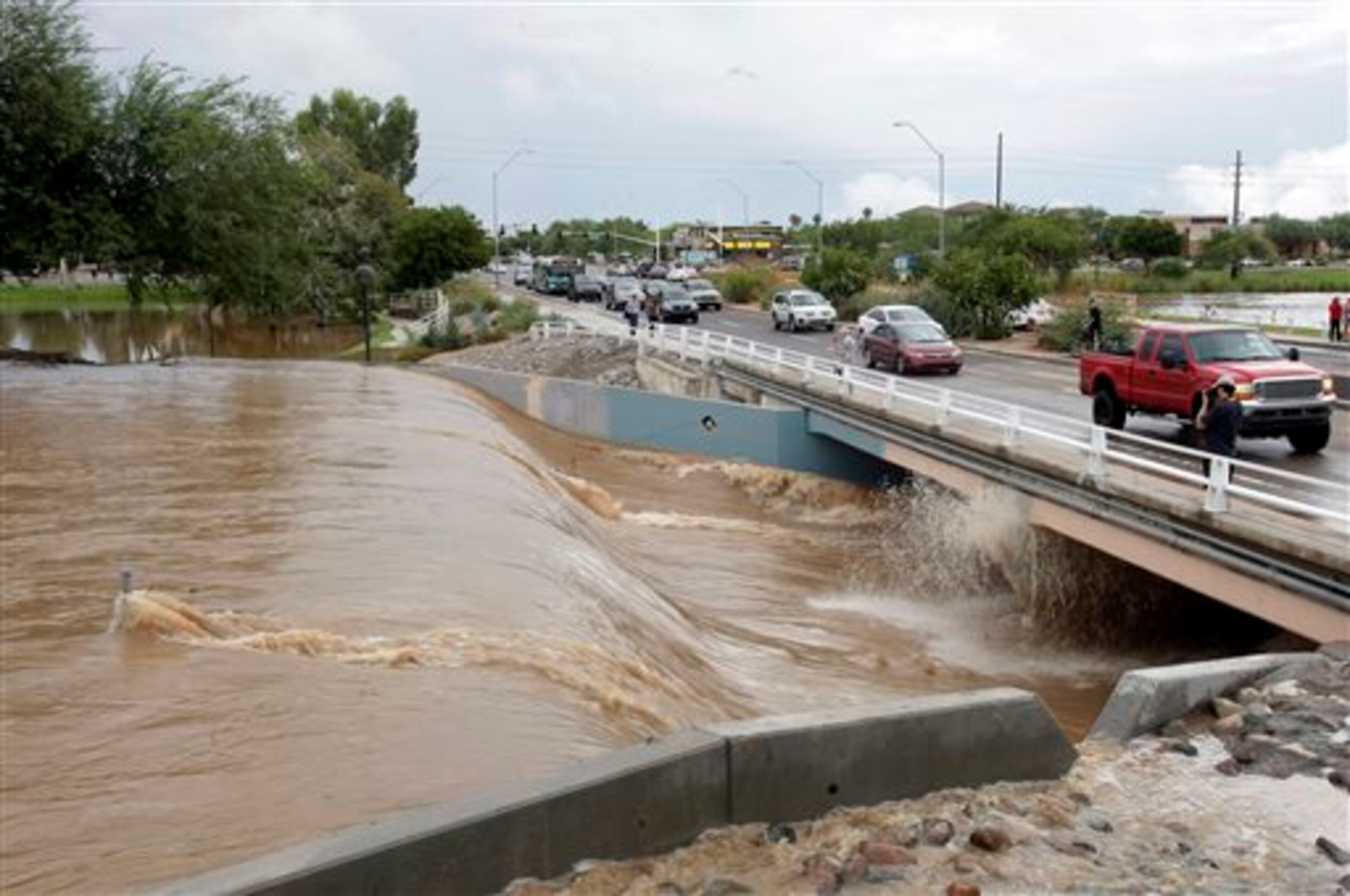Cars drive by flooding Monday, Sept. 8, 2014, in Scottsdale, Ariz. The remnants of Hurricane Norbert pushed into the desert Southwest and swamped Arizona Monday, breaking the previous record for rainfall in a single day in Phoenix. (AP Photo/Rick Scuteri)