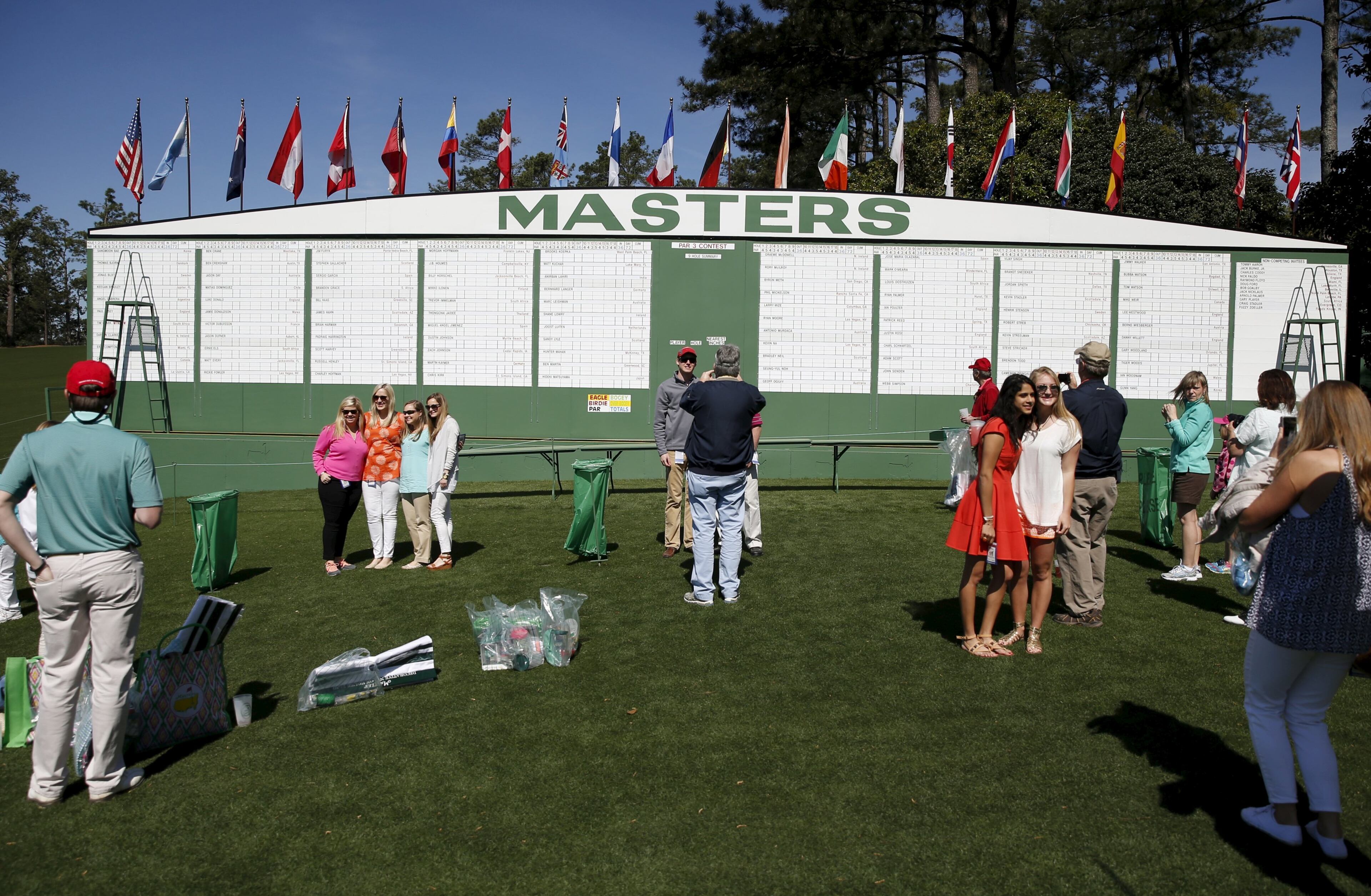 Golf patrons pose for pictures in front of the Masters score board during the Drive, Chip and Putt National Finals at the Augusta National Golf Course in Augusta, Georgia April 5, 2015. REUTERS/Phil Noble