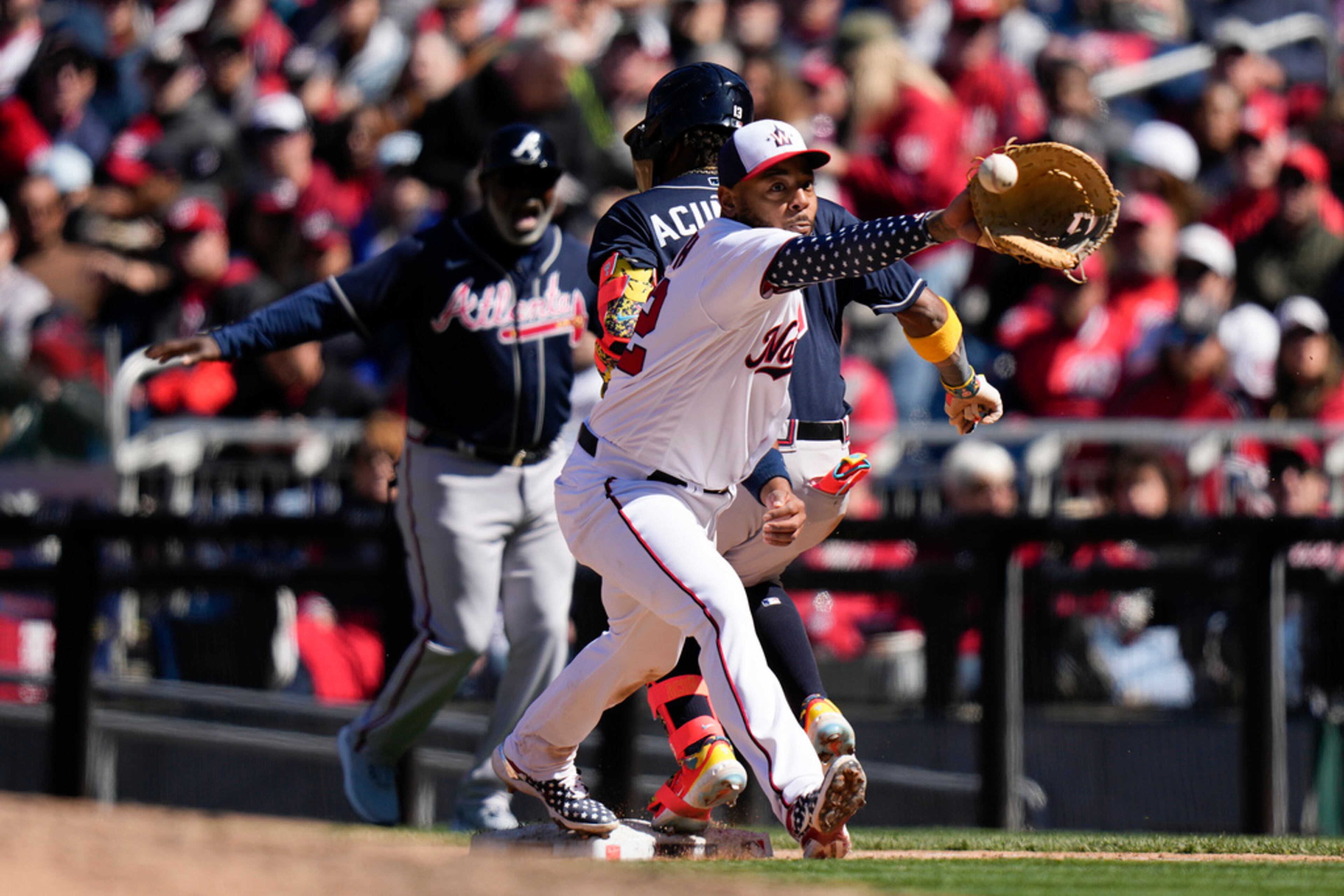Washington Nationals first baseman Dominic Smith reaches but can't make the catch in time as Atlanta Braves' Ronald Acuna Jr. singles during the fifth inning of an opening day baseball game at Nationals Park, Thursday, March 30, 2023, in Washington. (AP Photo/Alex Brandon)
