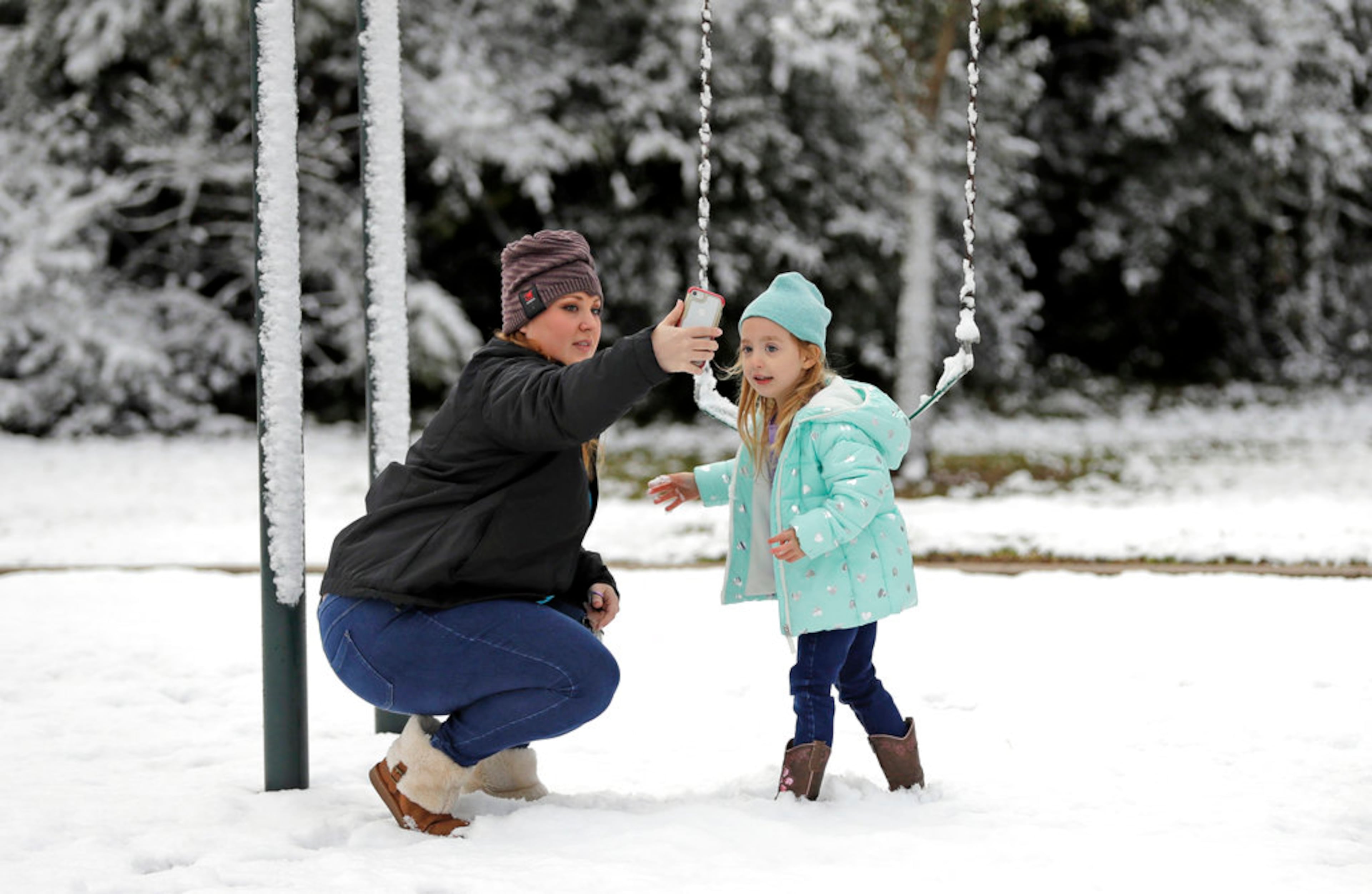 Cat Davis, left, takes a picture with her daughter, Lilly, 4, while playing in the snow at Meyer Park Friday, Dec. 8, 2017, in Spring, Texas, north of Houston. It was the first time Lilly has seen snow. Rare snowfall in many parts of southern Texas has knocked out power to thousands, caused numerous accidents along slick roadways and closed schools. The weather band brought snow to San Antonio, Corpus Christi, Houston and elsewhere. (AP Photo/David J. Phillip)
