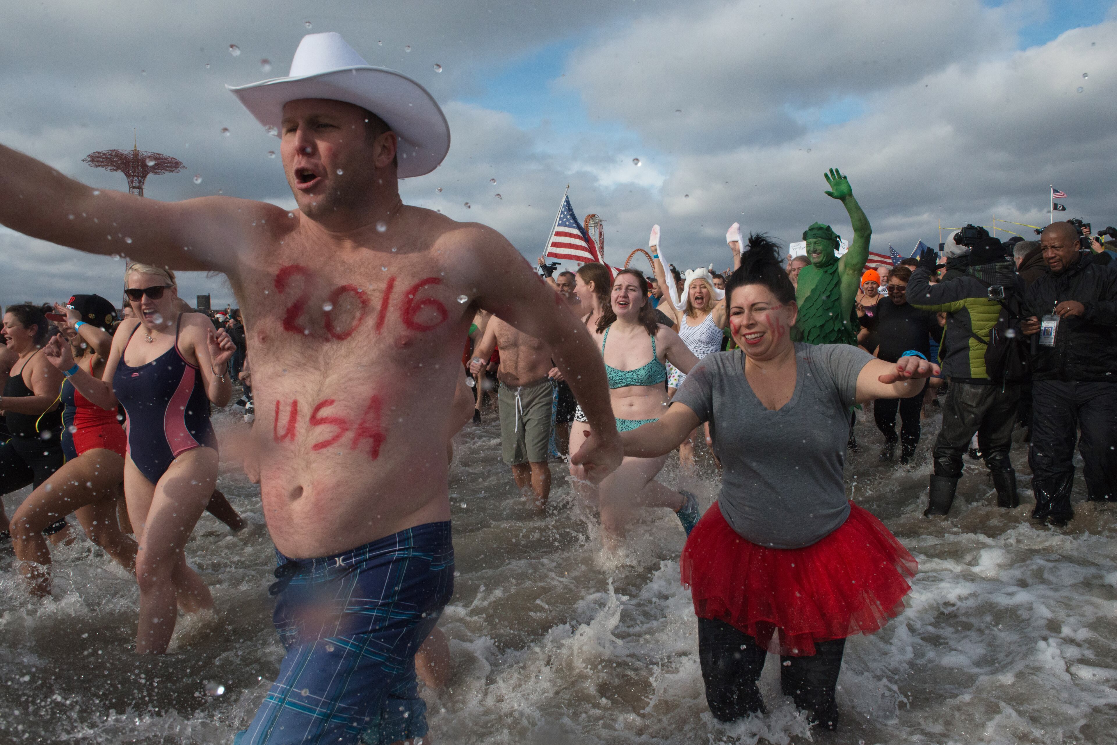 People in bathing suits run into the ocean during the annual Coney Island Polar Bear Club New Year's Day swim on January 1, 2016 in the Brooklyn borough of New York City. The Coney Island Polar Bear Club claims to be the oldest winter bathing organization in the U.S. and attracts hundreds to the beach for the annual swim in the Atlantic Ocean. (Photo by Stephanie Keith/Getty Images)