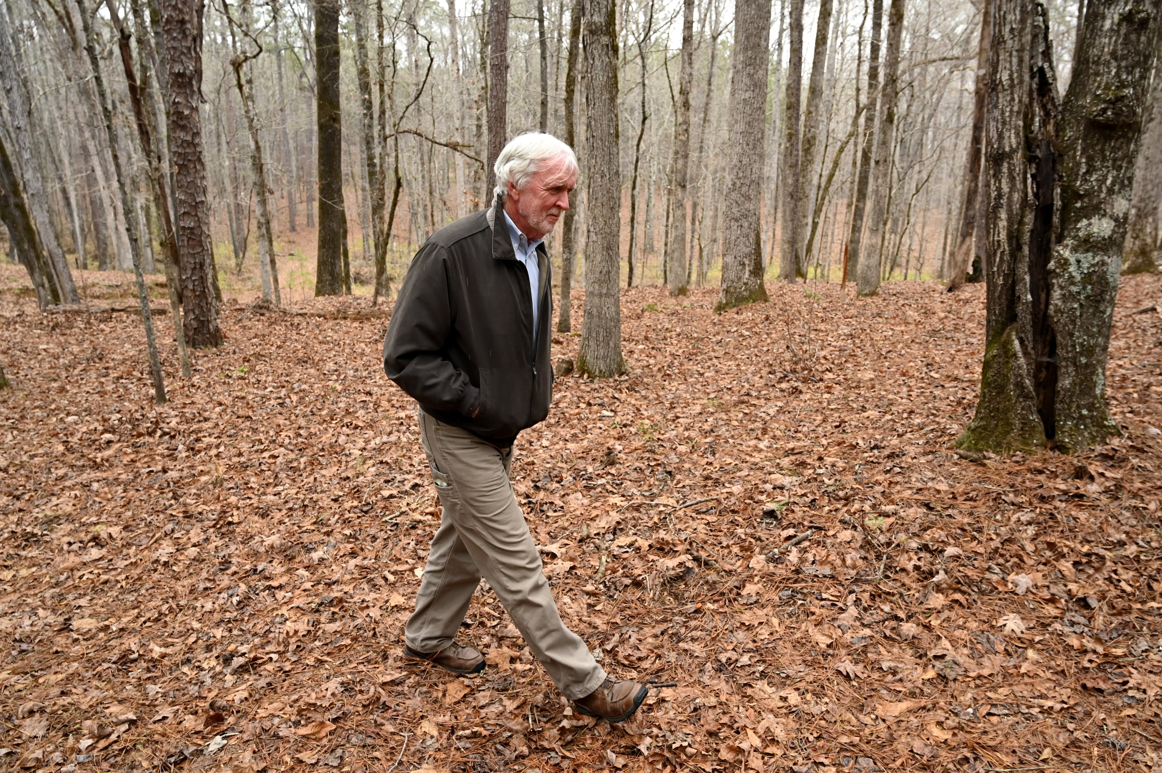 Allen Levi walks through the woods near his home on the way to his writing shed. (Hyosub Shin/AJC)