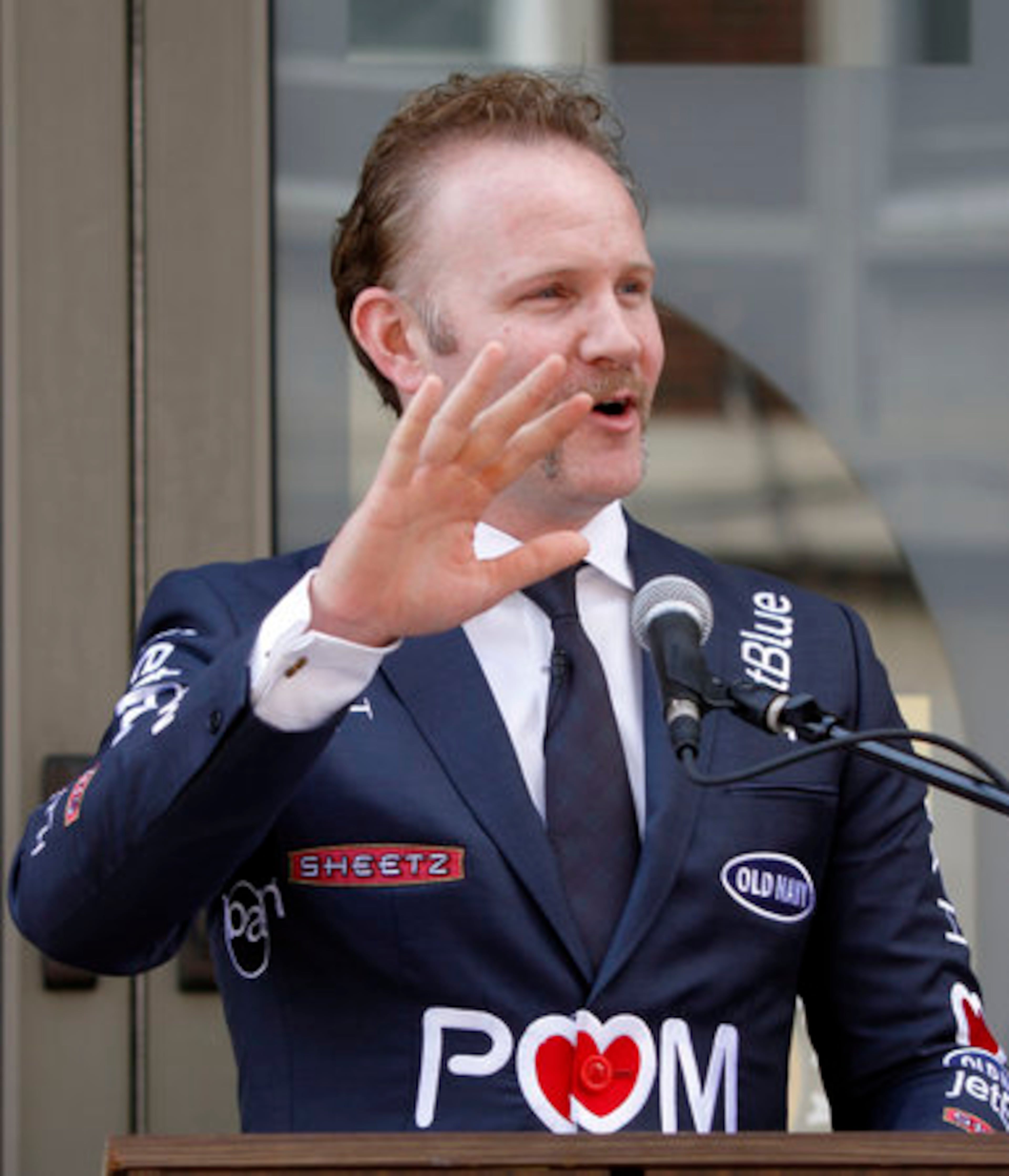 Spurlock, wearing a suit with sponsors names stitched onto it, addresses the crowd gathered before he and the mayor unveiled signs changing the name of Altoona, Pa.