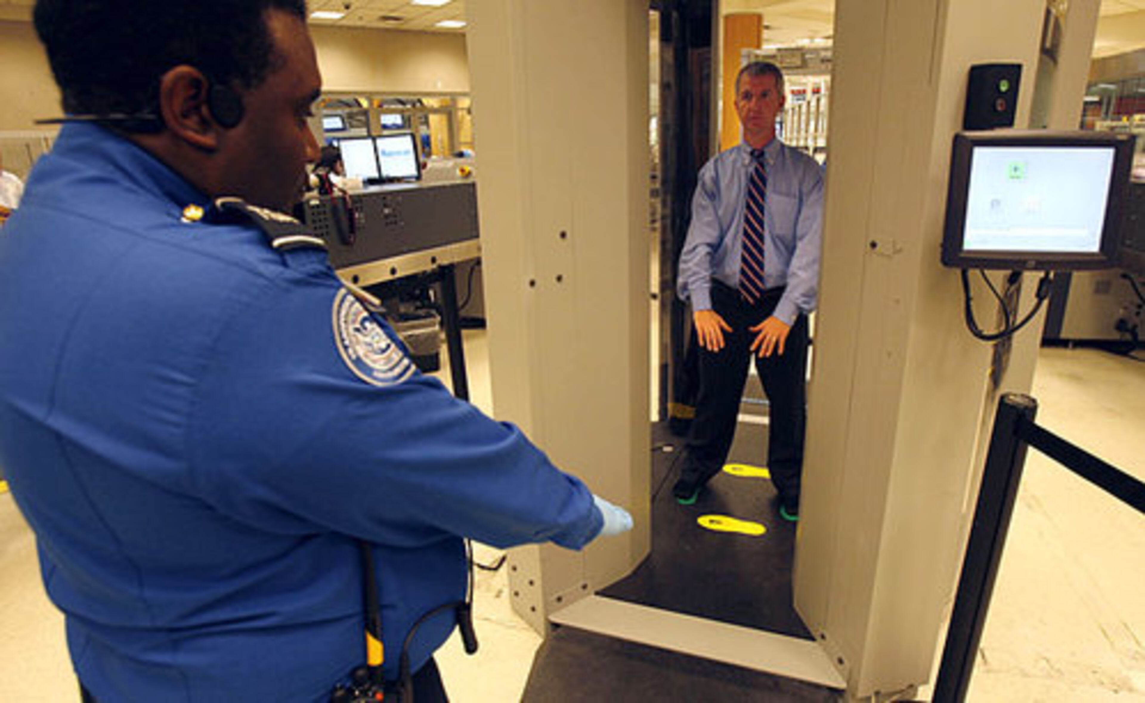 Allen assumes the 45-degree-angle pose in the scanner as Jefferson watches. The millimeter wave technology system will be used randomly at the airport starting Friday.