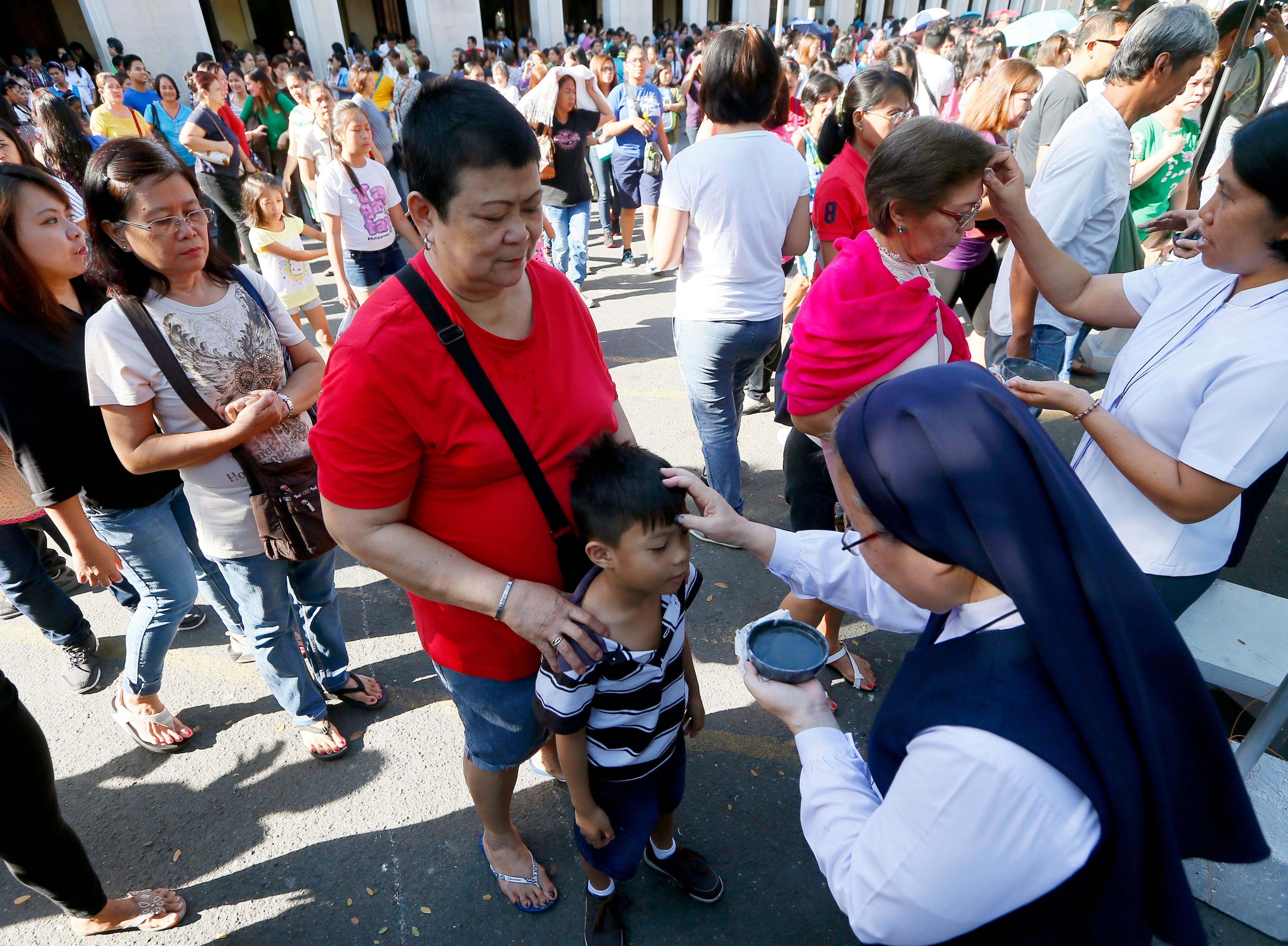 A Roman Catholic nun marks a sign of the cross on the foreheads of worshippers using ashes from burnt palm leaves in observance of Ash Wednesday at suburban Paranaque city, south of Manila,Philippines Wednesday, Feb. 10, 2016. Ash Wednesday ushers the 40-day season of Lent and is observed among Roman Catholics to remind mankind of being mortals.(AP Photo/Bullit Marquez)