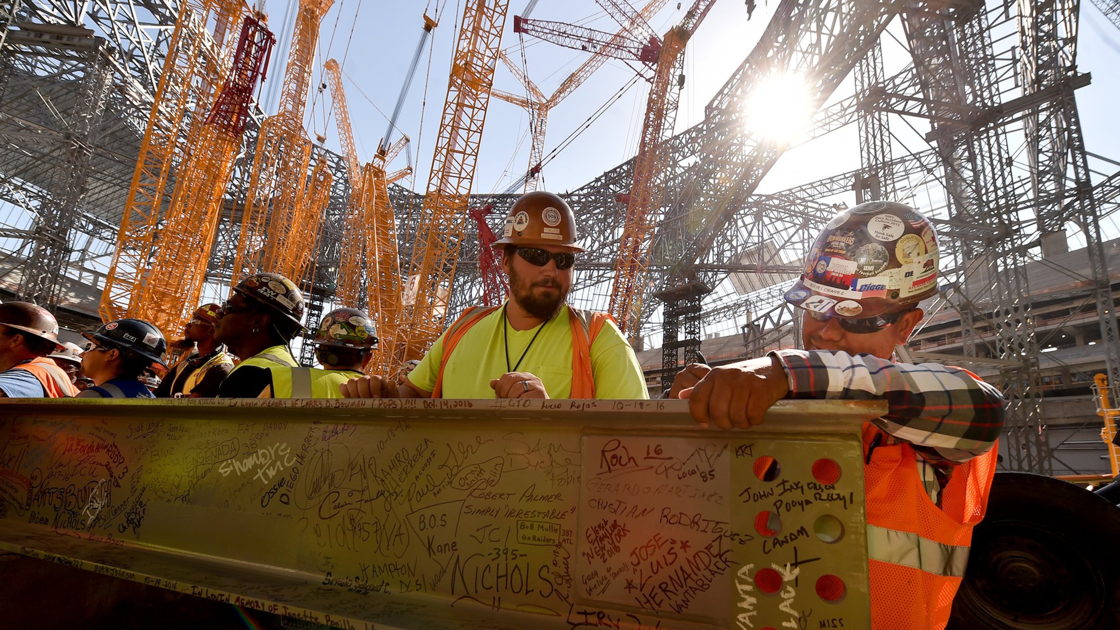 Construction workers sign a steel beam during an event Wednesday to celebrate the near completion of the fixed roof at Mercedes-Benz Stadium. BRANT SANDERLIN/BSANDERLIN@AJC.COM