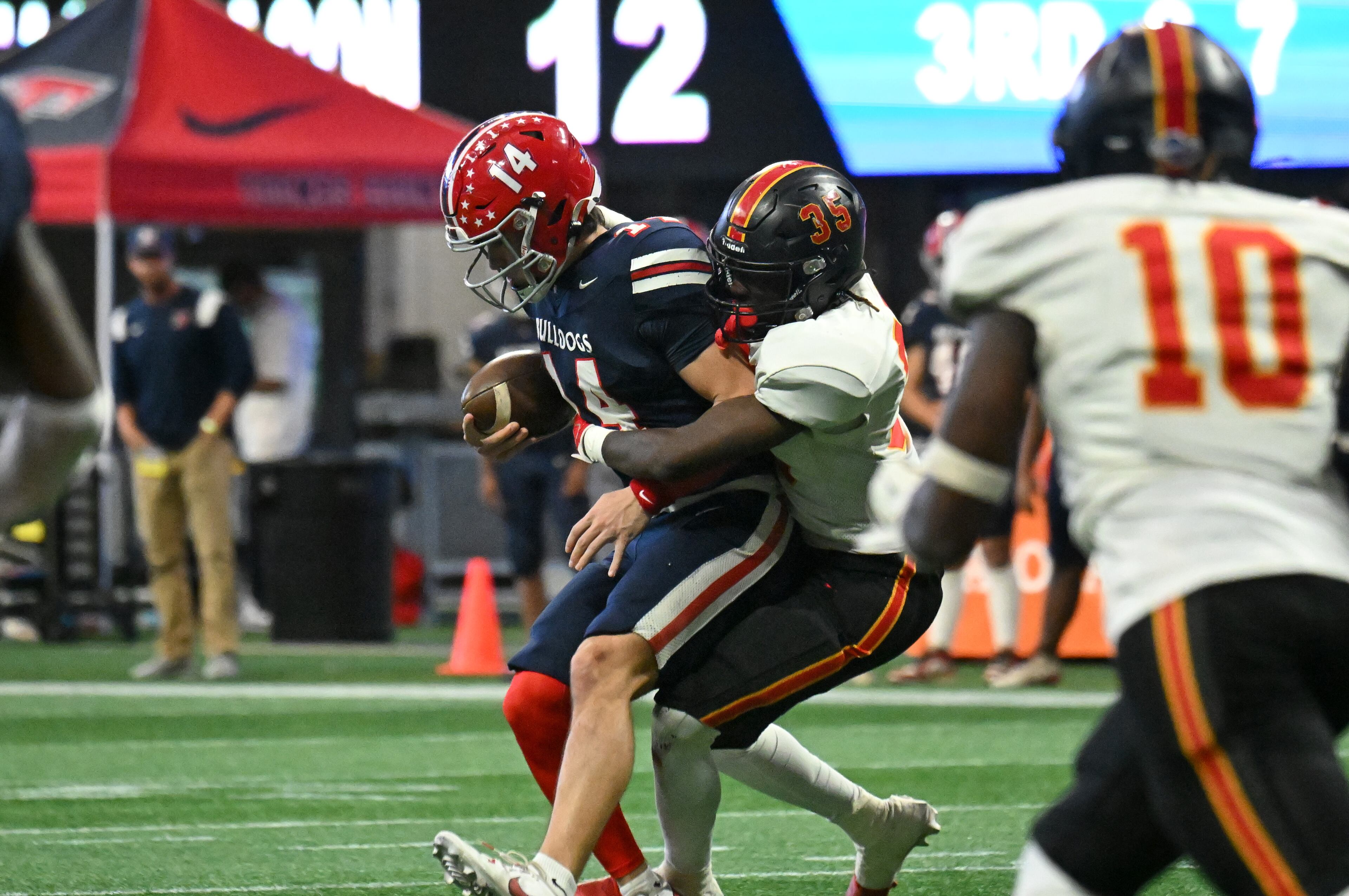 Toombs County's quarterback Tj Stanley (14) is sacked by Northeast's outside linebacker Tayvon Shivers (35) during the first half in GHSA Class A-Division State Championship game at Mercedes-Benz Stadium, Tuesday, December 17, 2024, in Atlanta. (Hyosub Shin / AJC)