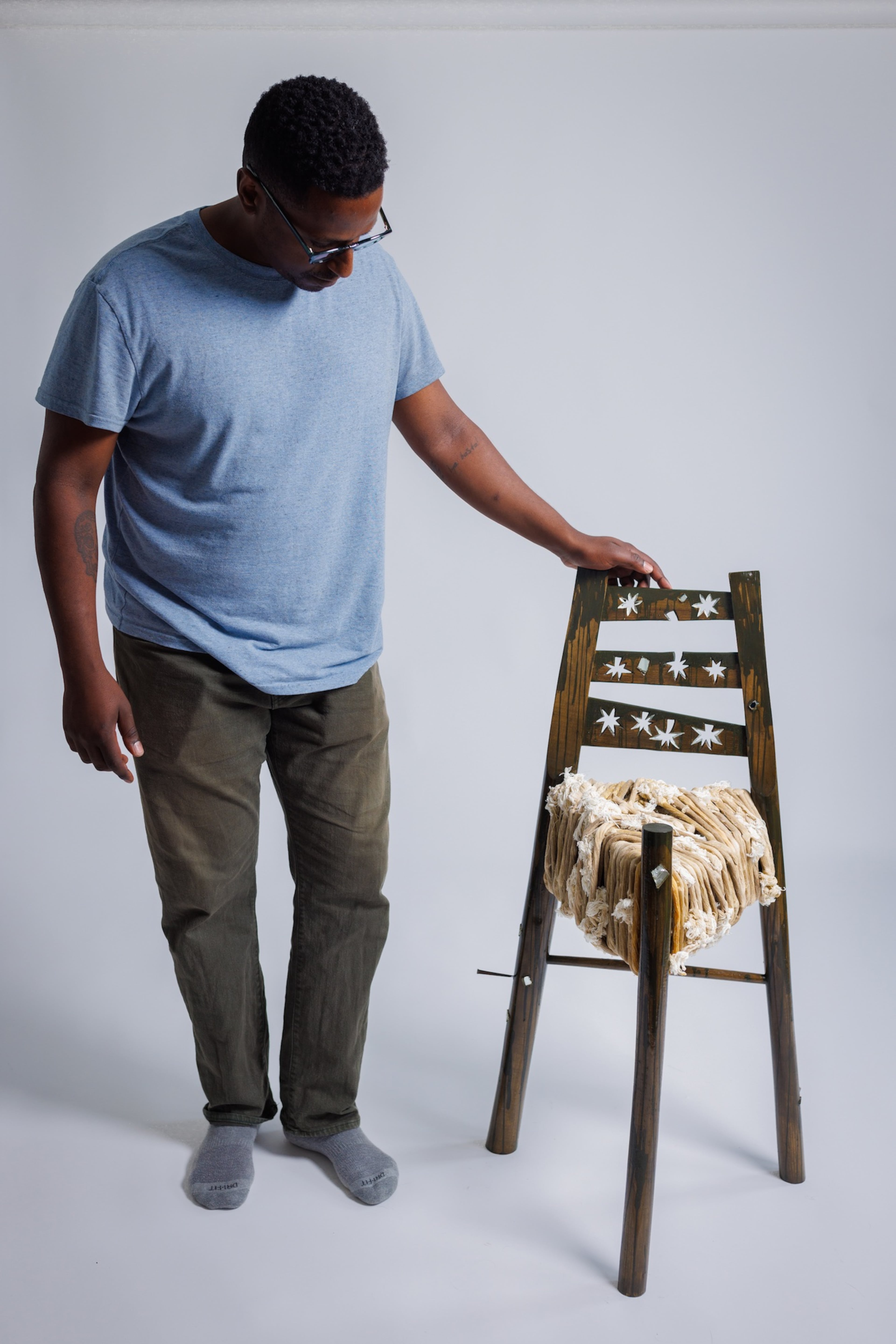 Robell Awake showcases his chair “Conjure Memory — Things Fall Apart,” made from Ethiopian religious candles, ash, hickory, maple, found mirror fragments, cut nail, a Crown Royal bag and milk paint. It is included in the collection at the Art Institute of Chicago. (Courtesy of Dustin Chambers)