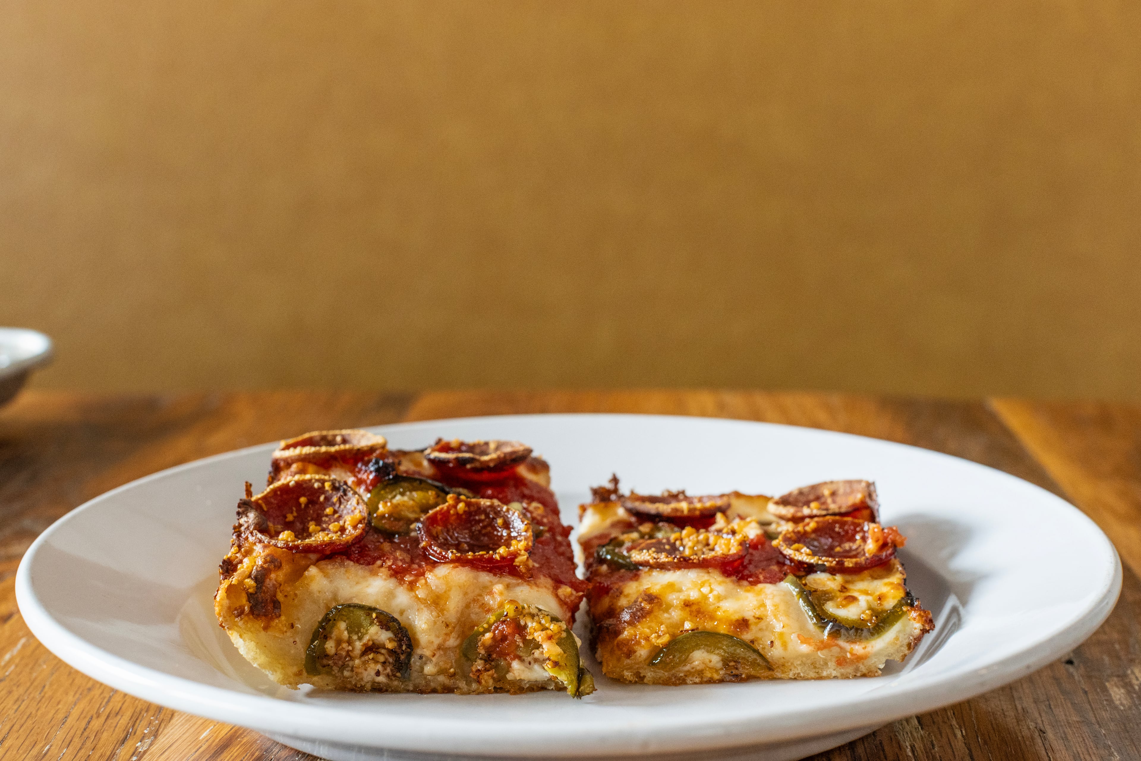 A piece of traditional, Detroit-style pizza (left) from Emmy Squared next to the restaurant's recently introduced skinny square pizza (right). (Courtesy of Emmy Squared)