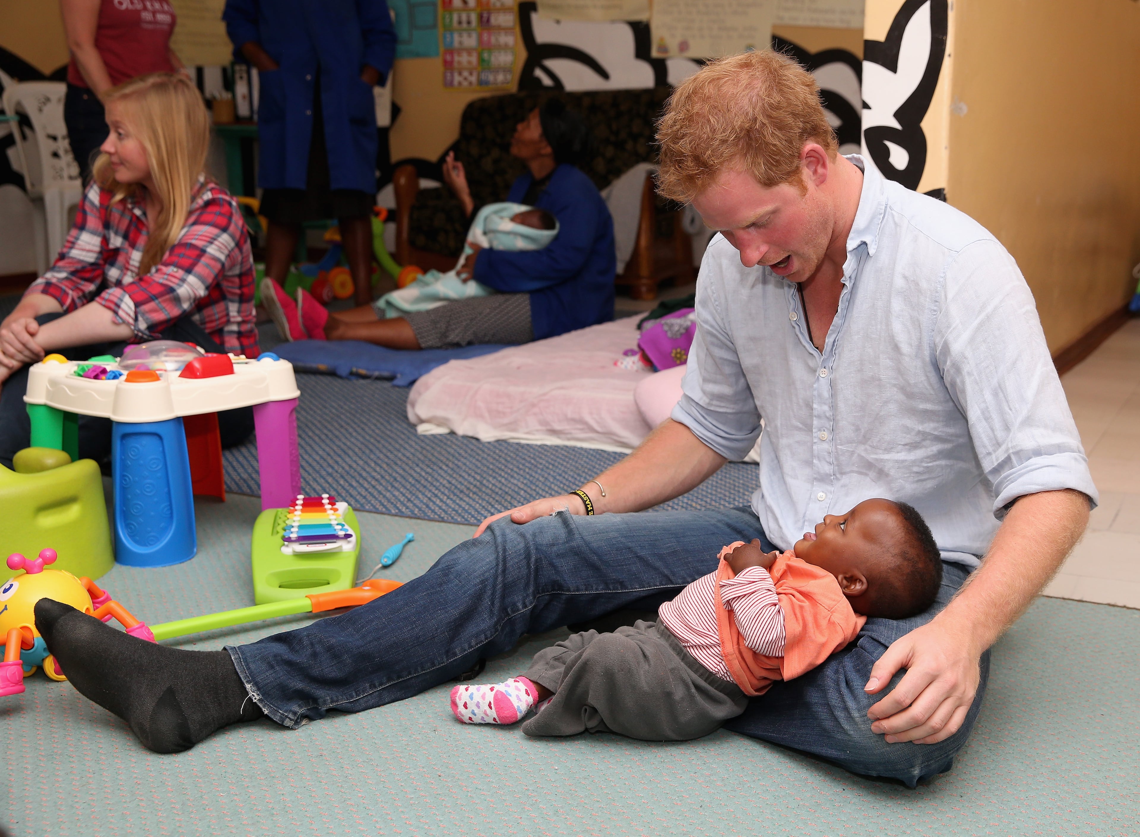 Prince Harry plays with two young children (who are going through a programme for malnourishment) during a visit to the organisation supported by Sentebale 'Touching Tiny Lives' on December 8, 2014 in Mokhotlong, Lesotho. Prince Harry was visiting Lesotho to see the work of his charity Sentebale. Sentebale provides healthcare and education to vulnerable children in Lesotho, Southern Africa. The particular theme of his visit was to check on the progress of the Mamohato Childrens Centre which will provide vital support to children affected by HIV. Prince Harry founded Sentebale (which means Forget Me Not in Sesotho) with Prince Seeiso in 2006. (Photo by Chris Jackson/Getty Images for Sentebale)