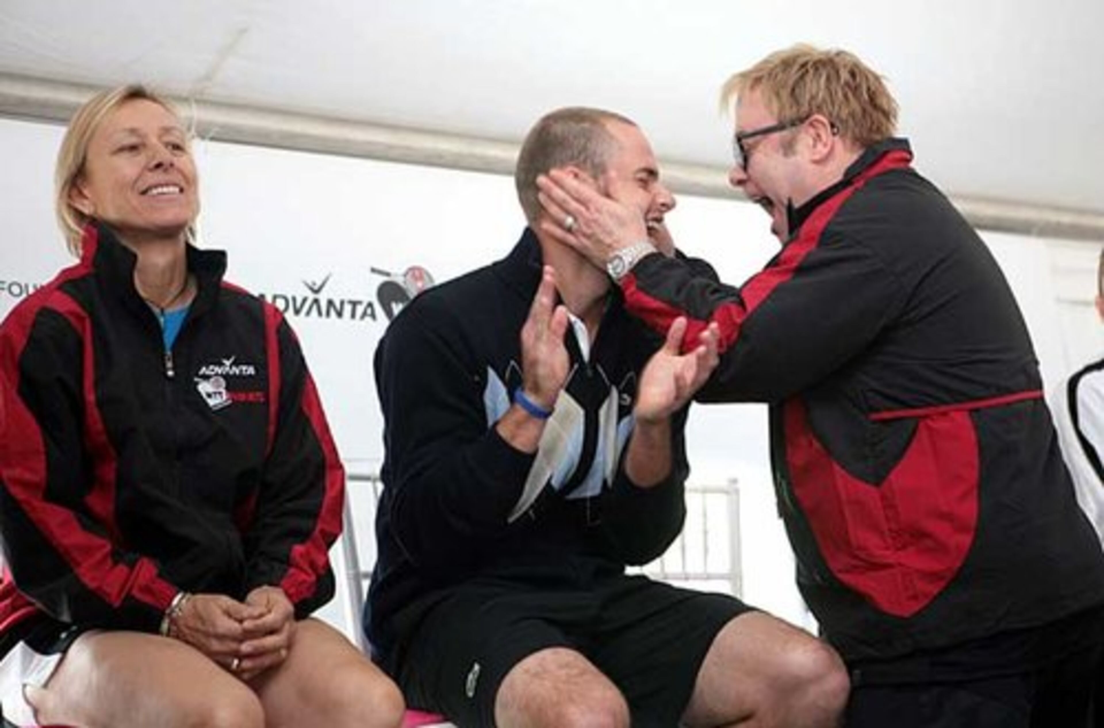 As tennis legend Martina Navratilova (left) sits by, tennis star Andy Roddick and Elton John share a laugh during the live auction segment of the Advanta WTT Smash Hits.
