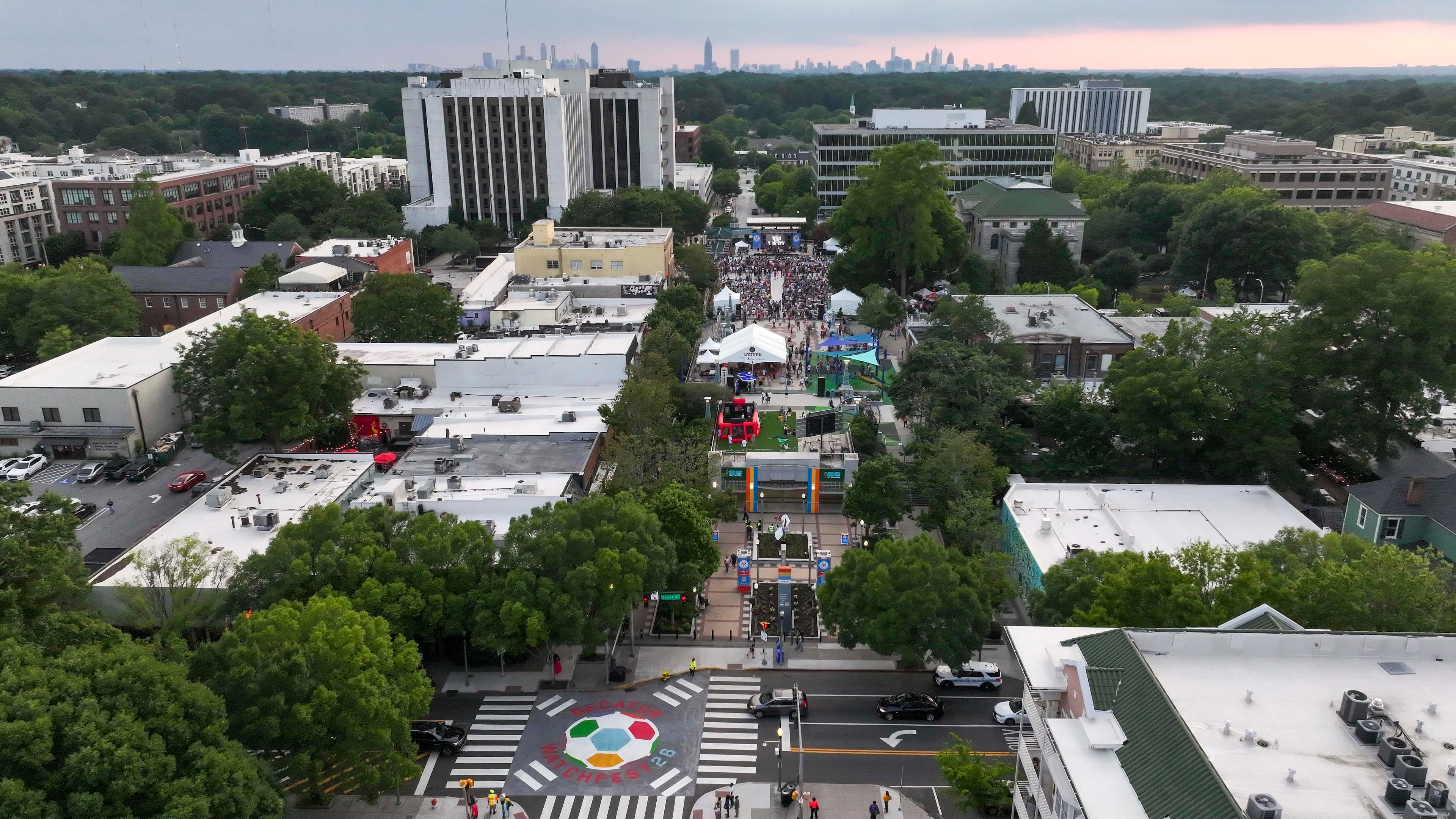 An aerial image shows Decatur Square with the Atlanta skyline in the distance as the War and Treaty performs at Decatur WatchFest ’26 on Thursday, June 25, 2026. (Miguel Martinez/AJC)