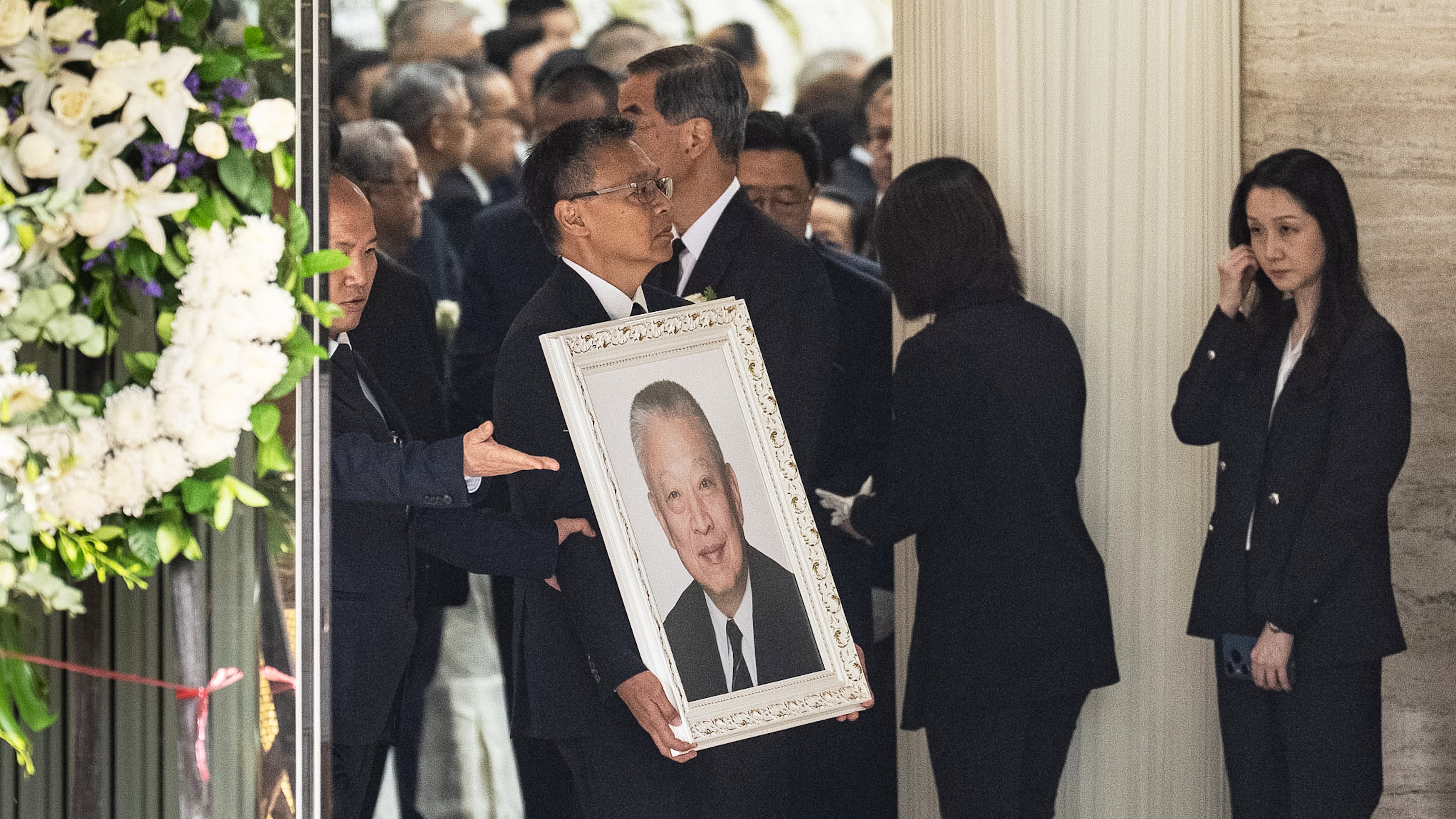 Andy Tung, son of former Hong Kong leader Tung Chee-hwa, carries his father's portrait at a funeral home in Hong Kong, Sunday, Sept. 20, 2026. (AP Photo/Chan Long Hei)