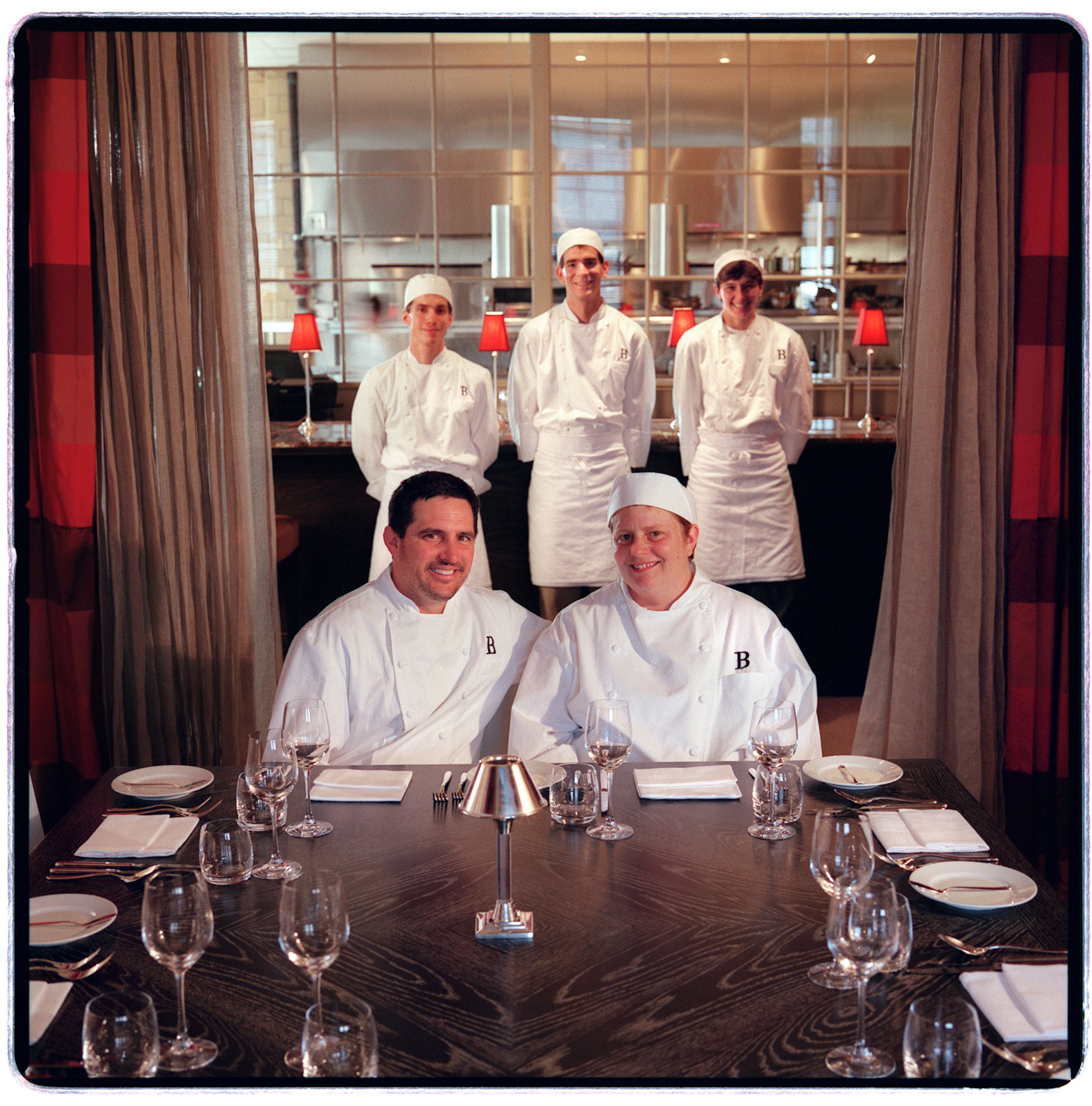 Bacchanalia Chef/Owners (l-r front) Clifford Harrison & Anne Quatrano sit at the chefs table in 2000 as their kitchen staff (l-r back) sous chef - Gregory Dunmore, Ex. day chef - Daniel Porubiansky & sous chef - Claudia Nesbit stand at the bar. The glassed in kitchen is in the background.