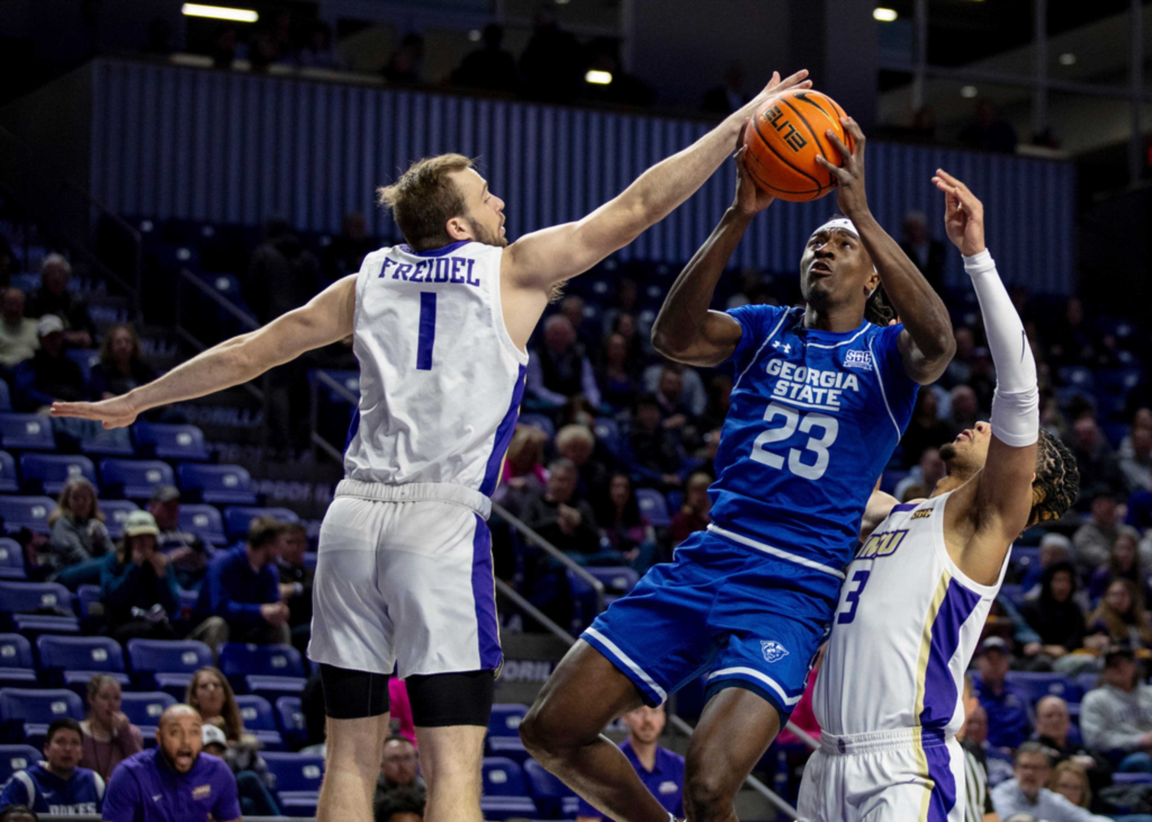 Georgia State forward Leslie Nkereuwem (23) shoots between James Madison guard Noah Freidel (1) and forward T.J. Bickerstaff (3) during the first half of an NCAA college basketball game in Harrisonburg, Va., Thursday, Feb. 15, 2024. (Daniel Lin/Daily News-Record via AP)
