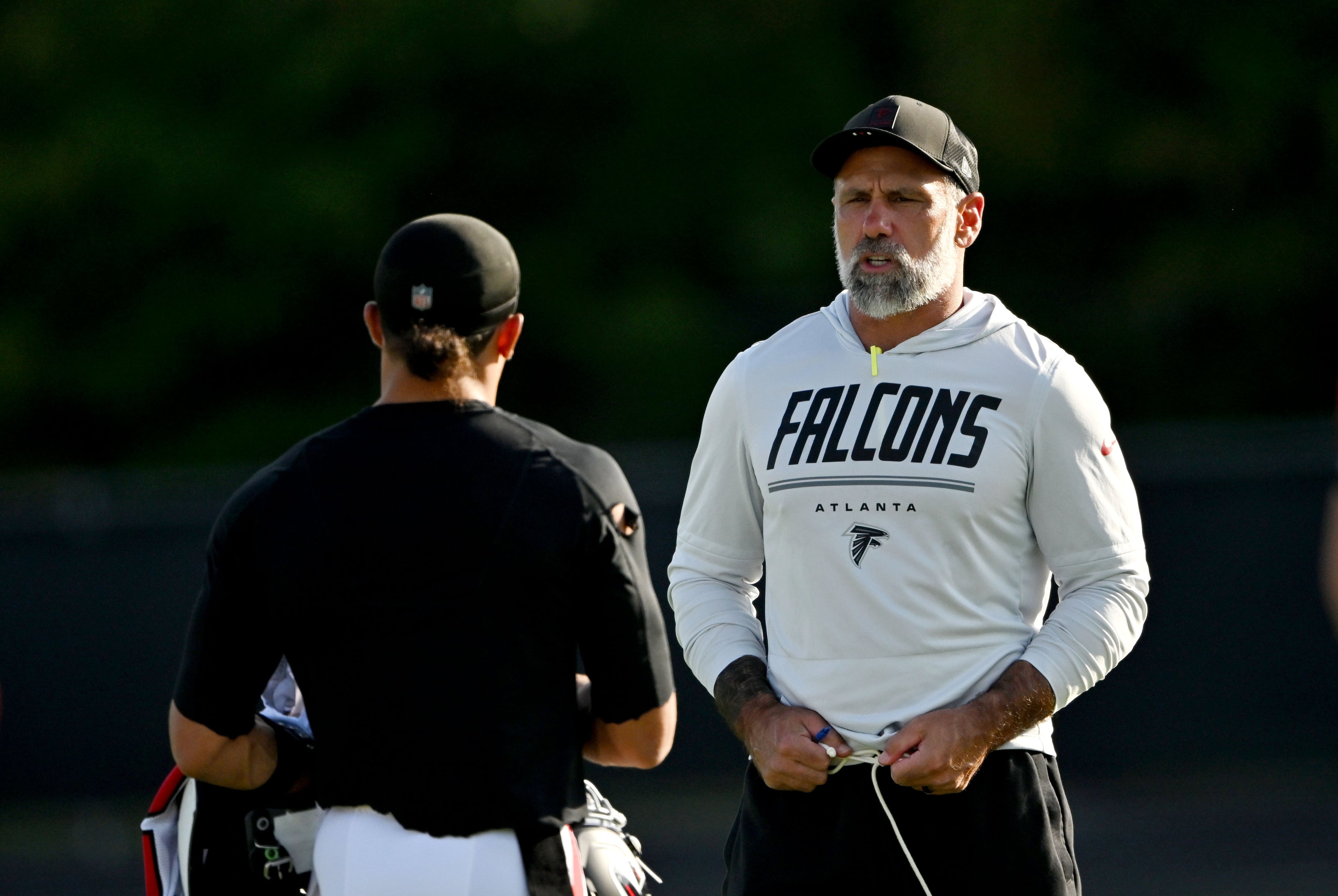 Falcons defensive coordinator Jeff Ulbrich talks to a staff member before "Saturday Night Lights" practice Saturday, Aug. 8, 2026, at Lanier High School in Sugar Hill. (Hyosub Shin/AJC)