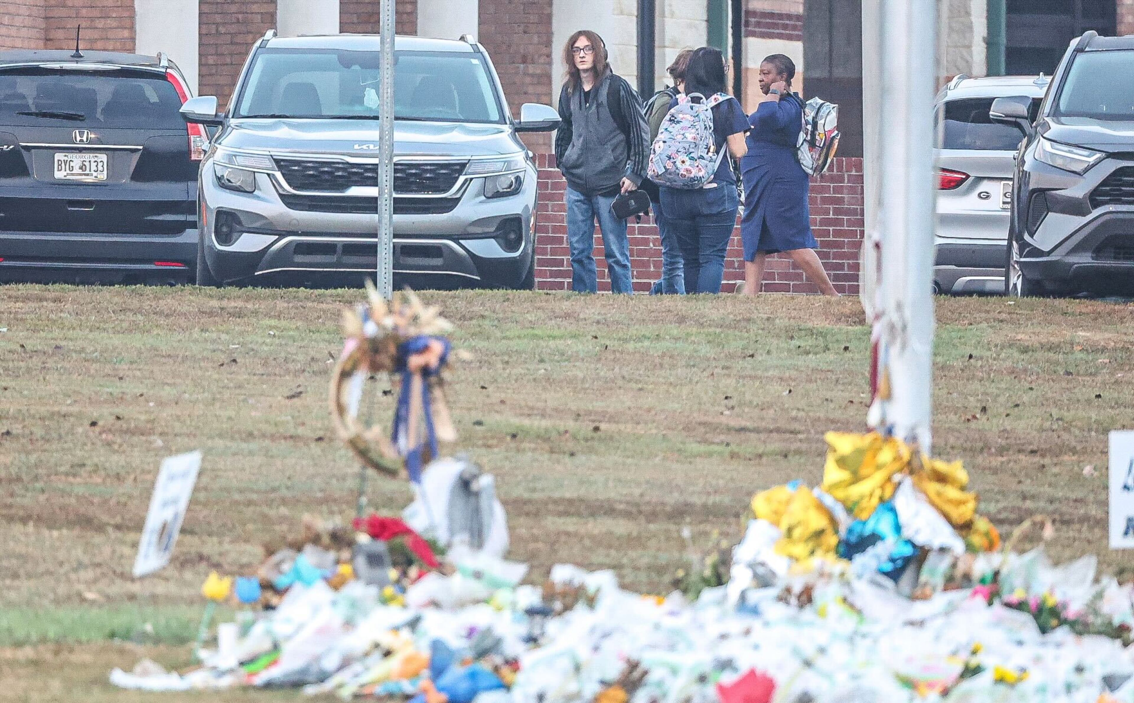 A sign with big blue letters that reads ‘Love will prevail” is perched near the entrance. U.S. and Georgia flags are at half-mast. The flagpole is surrounded by flowers, balloons and wreaths left in memory of the four people shot and killed here less than three weeks ago.